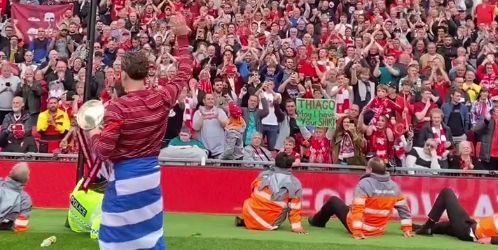 Kostas Tsimikas thanks Liverpool fans as he poses with a Greek flag and the Carabao Cup in front of the Kop