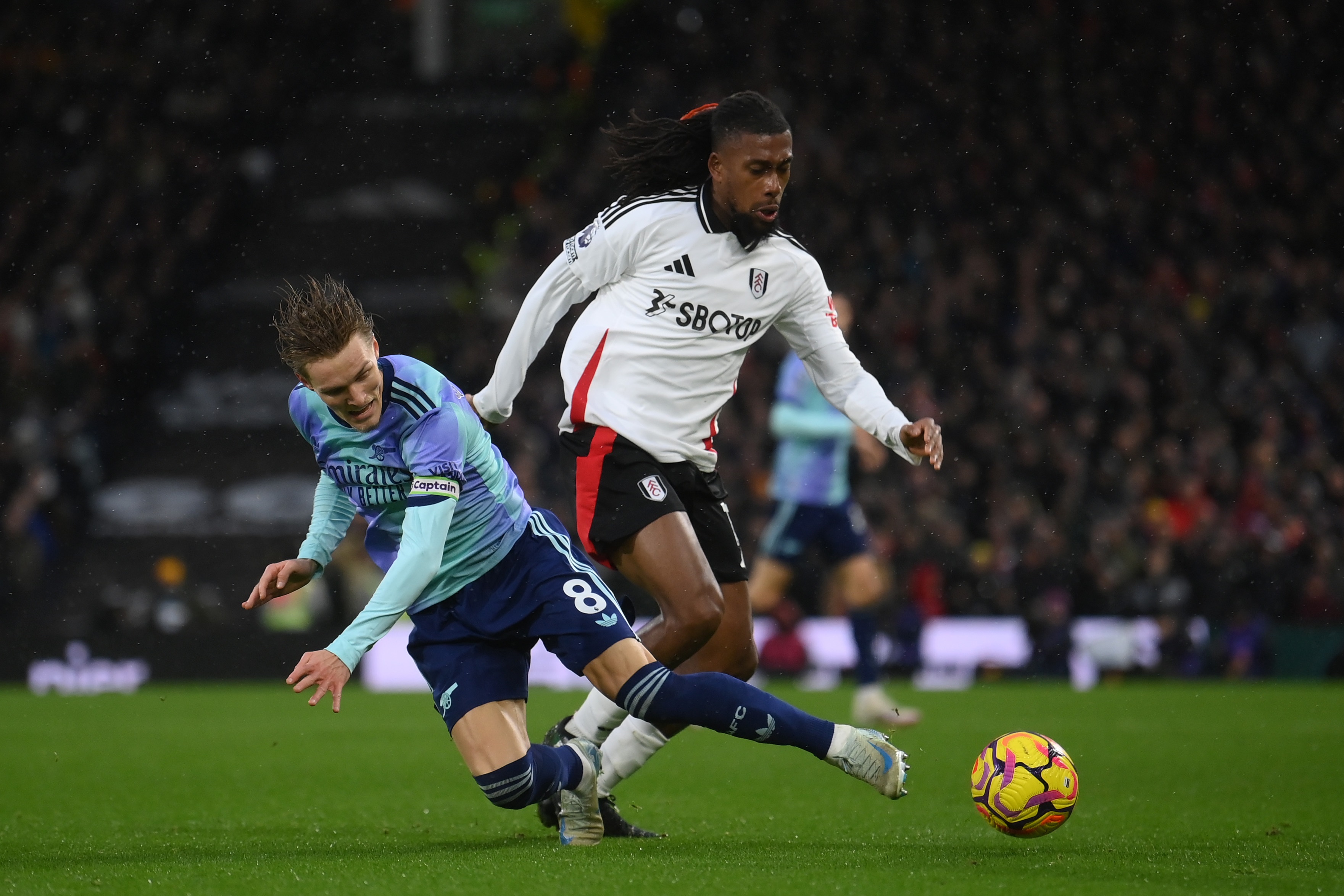 Martin Odegaard of Arsenal is challenged by Alex Iwobi of Fulham.