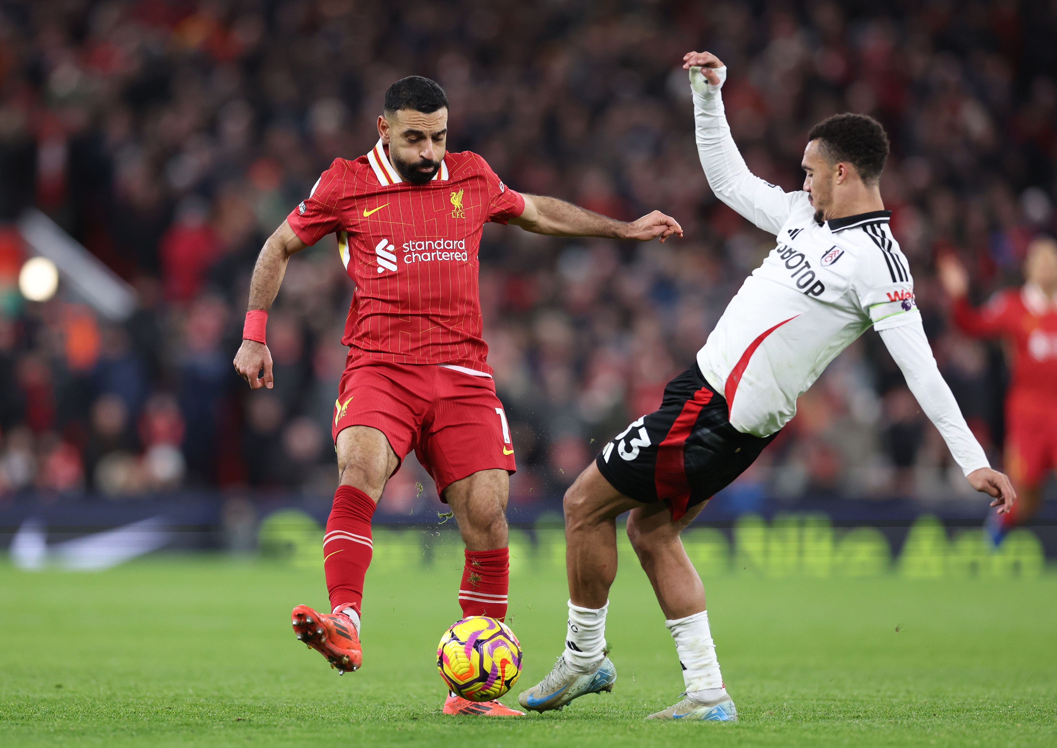 Mo Salah plays a pass as Antonee Robinson attempts a tackle.