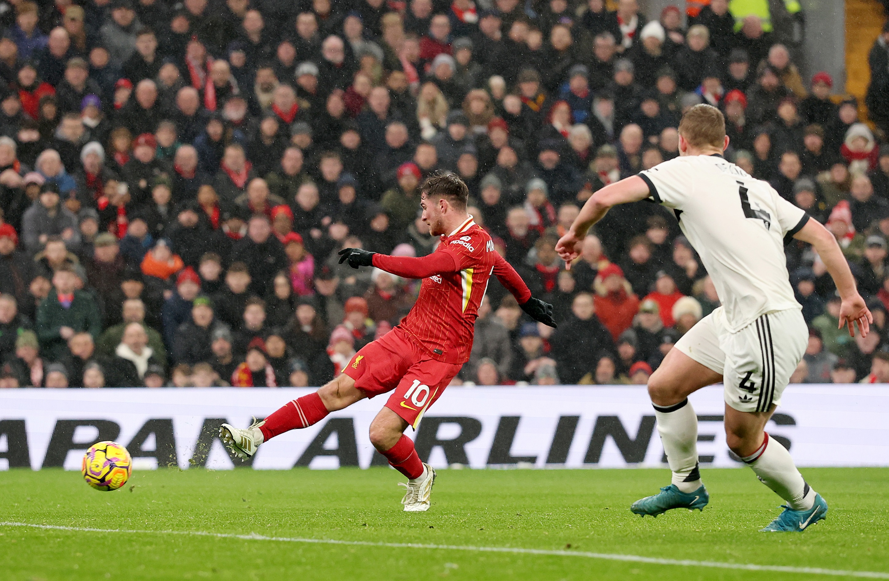 Alexis Mac Allister passes the ball at Anfield against Manchester United.