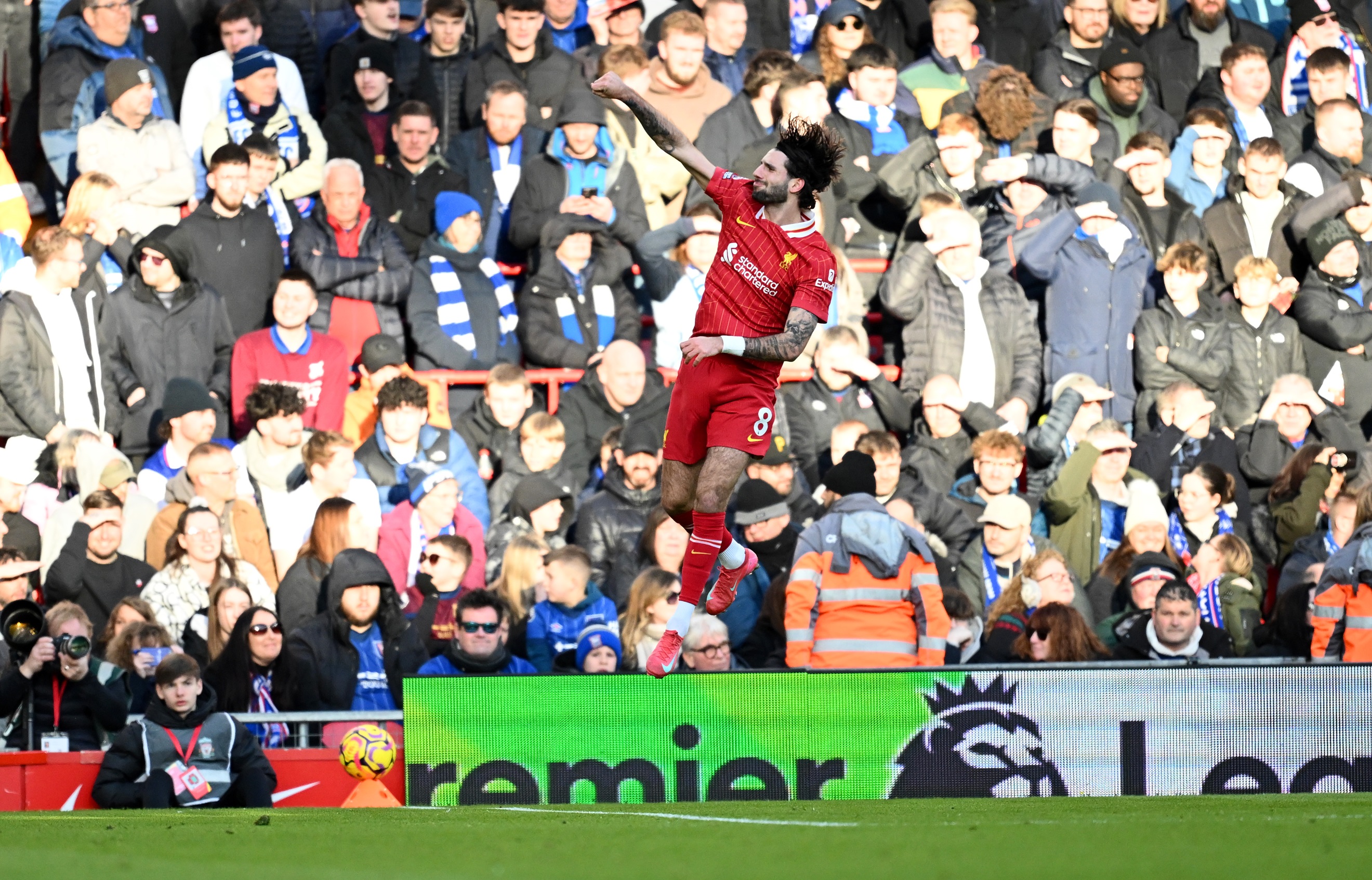 Liverpool midfielder Dominik Szoboszlai jumps and punches the air after scoring a goal.