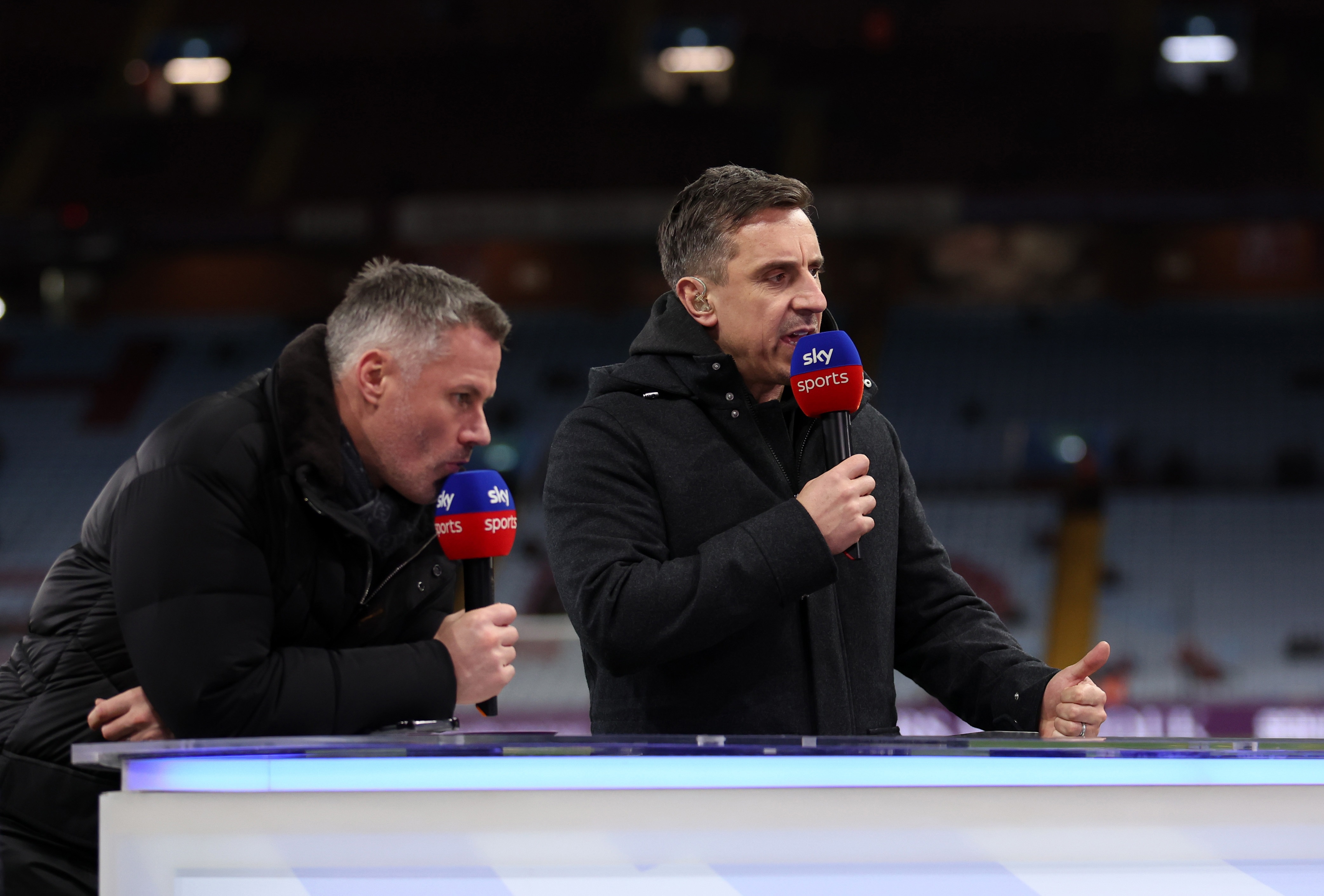 Jamie Carragher and Gary Neville speak into Sky Sports microphones.