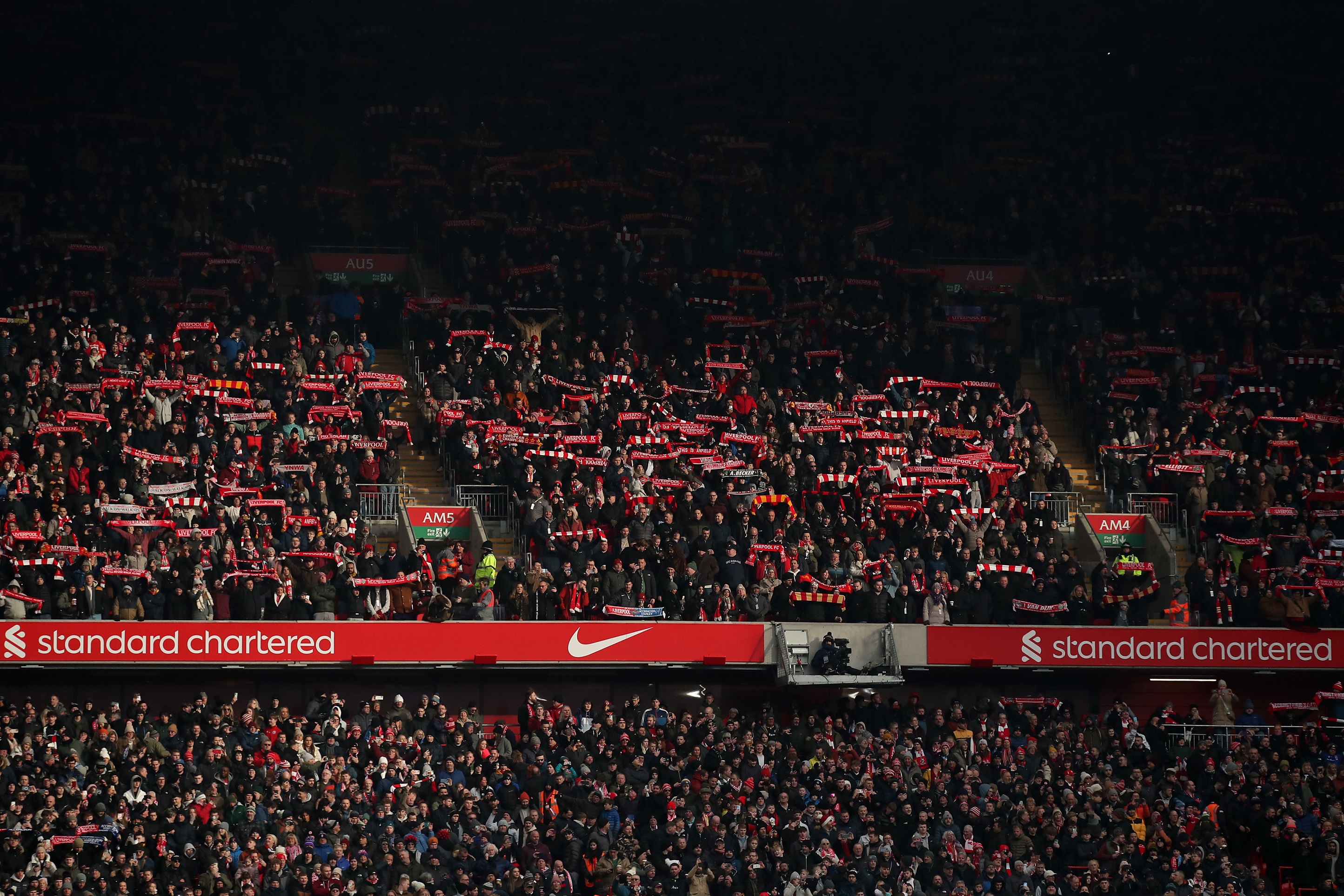 Liverpool fans raise their scarves in support of the team at Anfield.