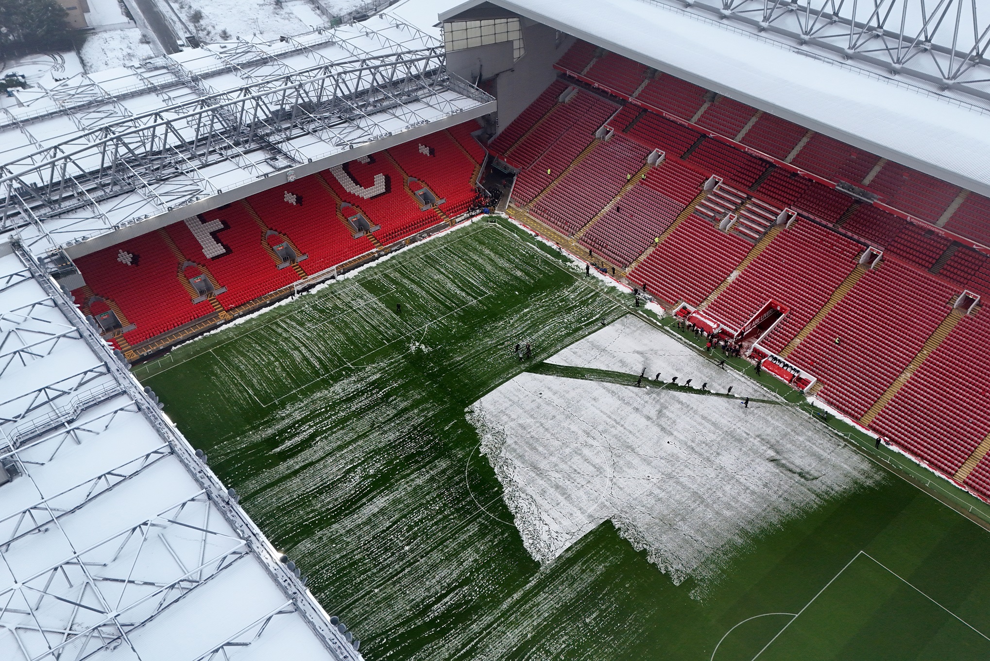 An overhead picture of Anfield Stadium as staff try and clear snow off the grass.