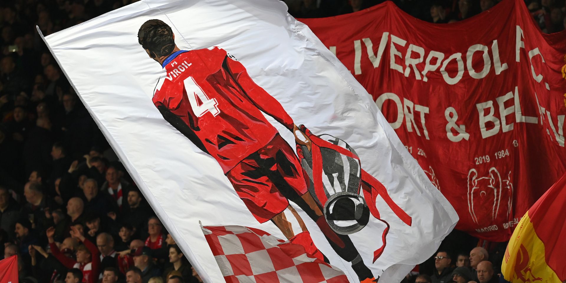 A flag of Virgil van Dijk with the Champions League trophy on the Kop