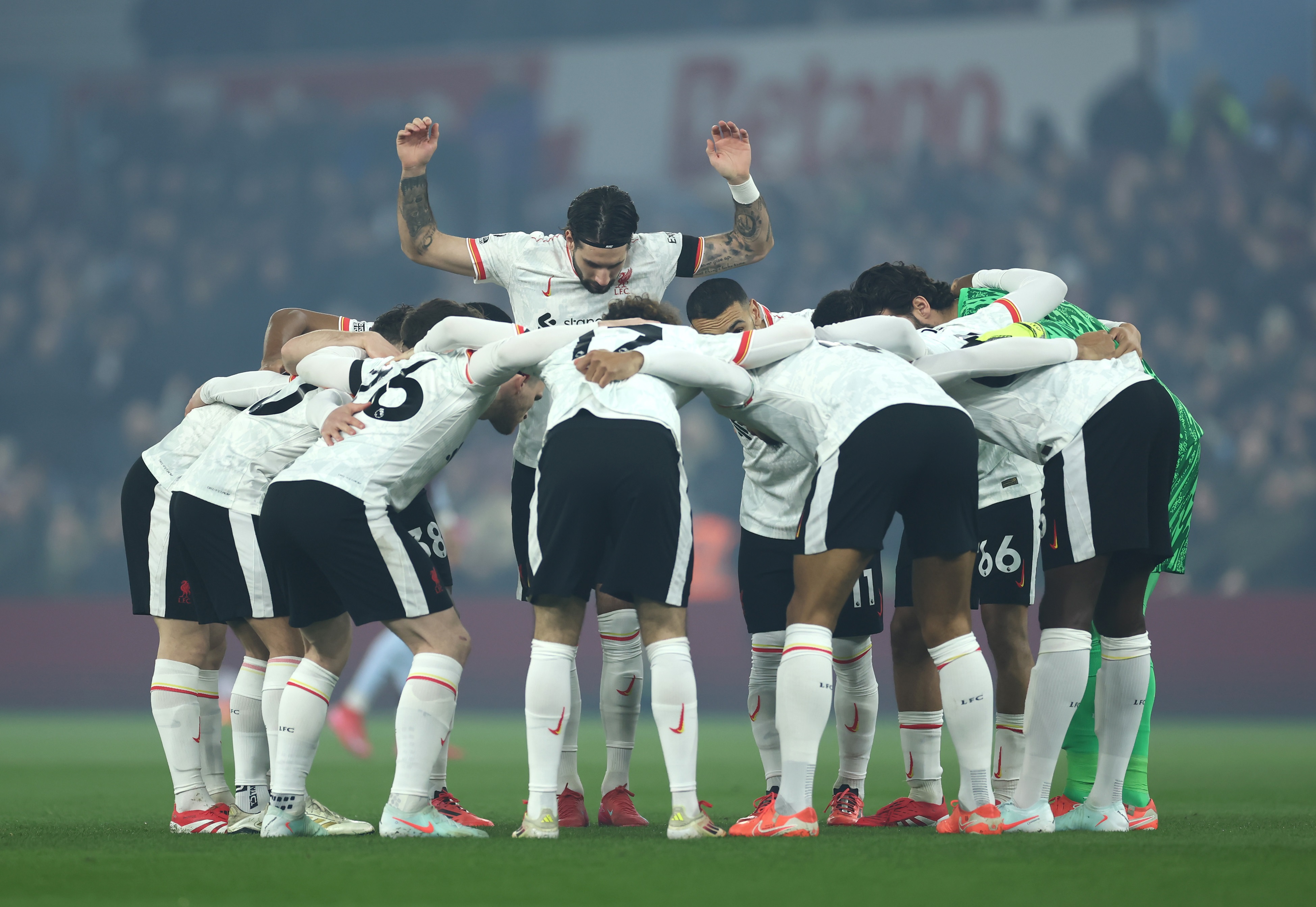 Curtis Jones gathers in a huddle with Liverpool players.