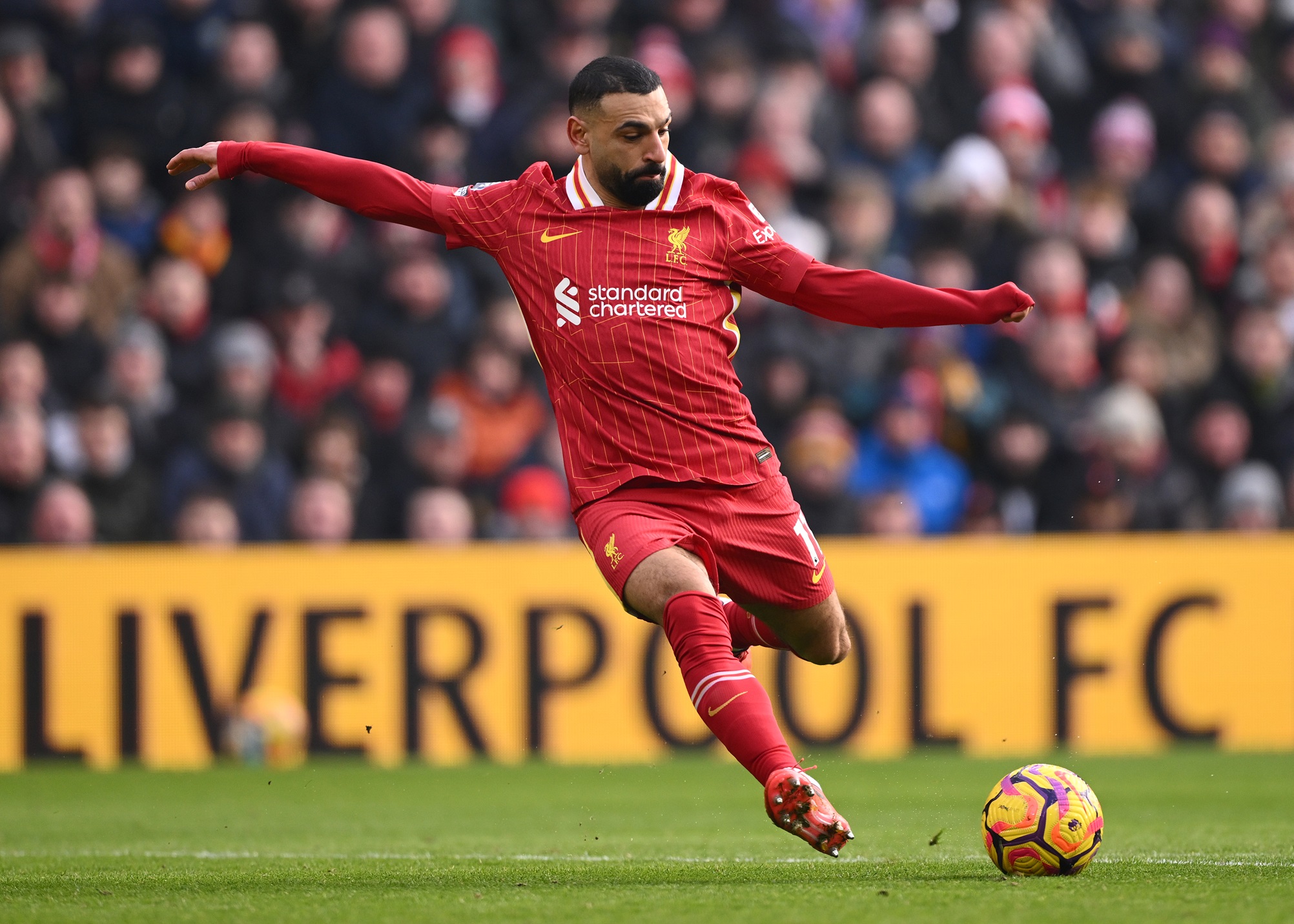 Liverpool winger Mo Salah shoots the ball during Premier League game.