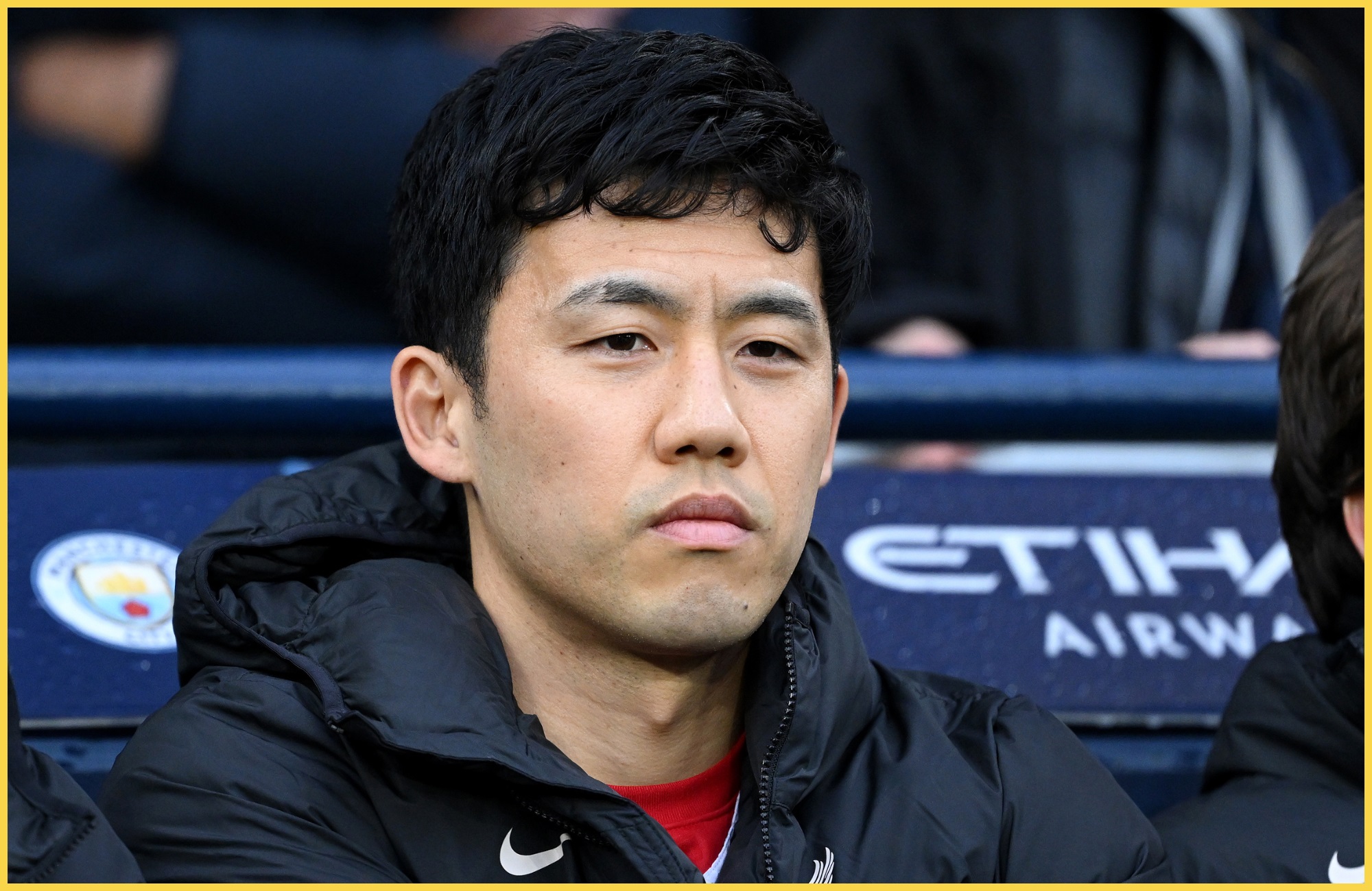 Wataru Endo looks on from the Liverpool bench at the Etihad Stadium.