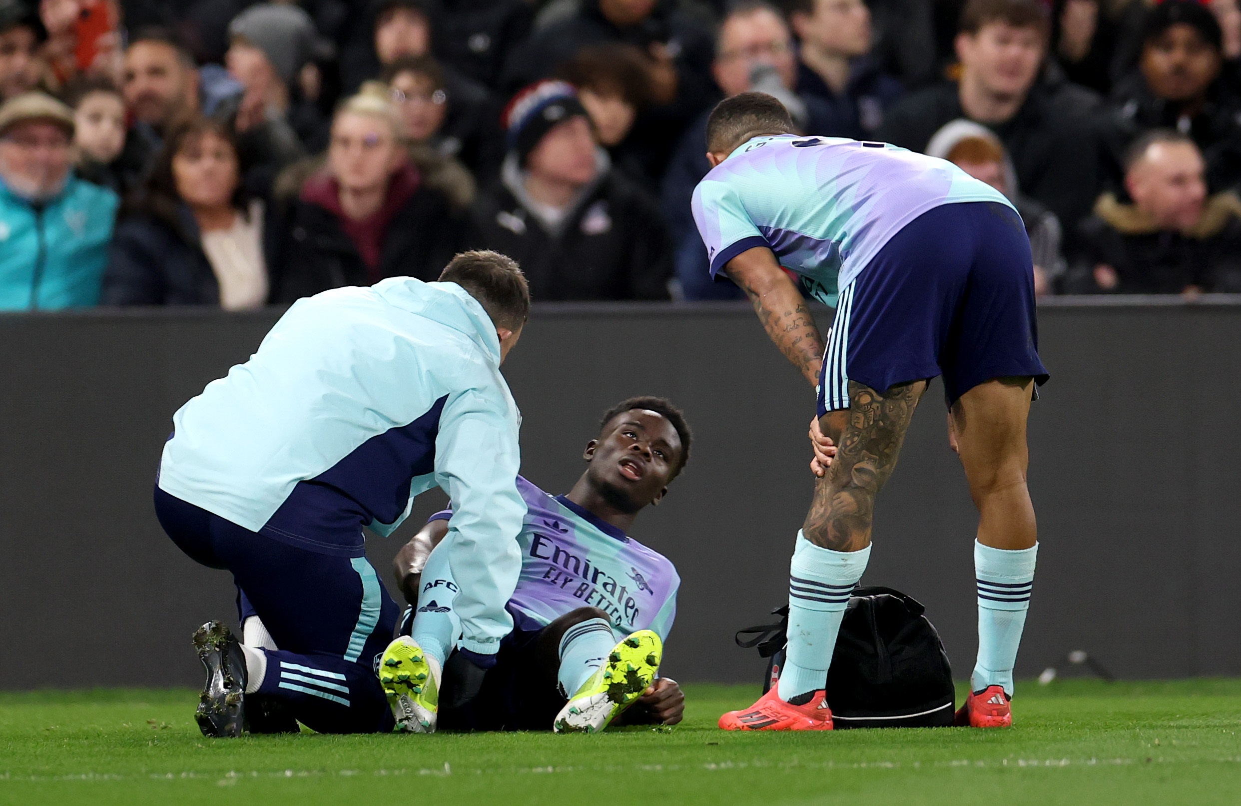 Arsenal star Bukayo Saka lies on the ground receiving medical treatment.