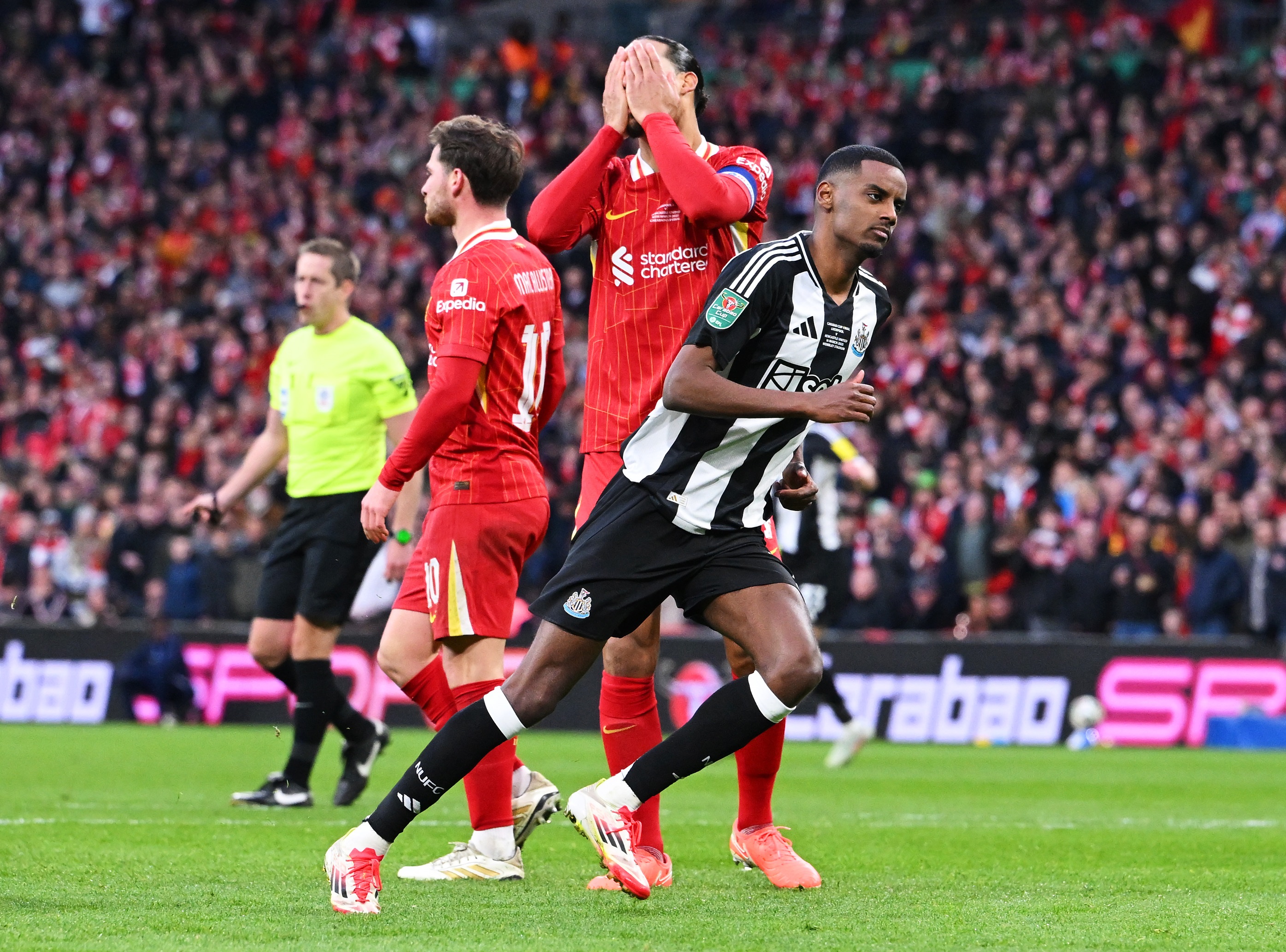 Virgil van Dijk covers his face with his hands as Alexander Isak races away.