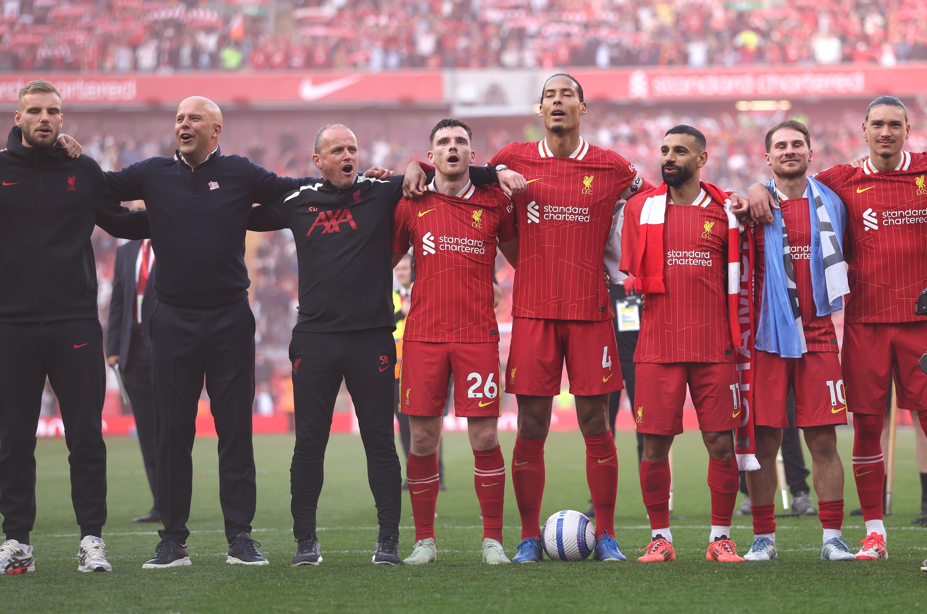 Arne Slot stands in a line with Liverpool players at Anfield.