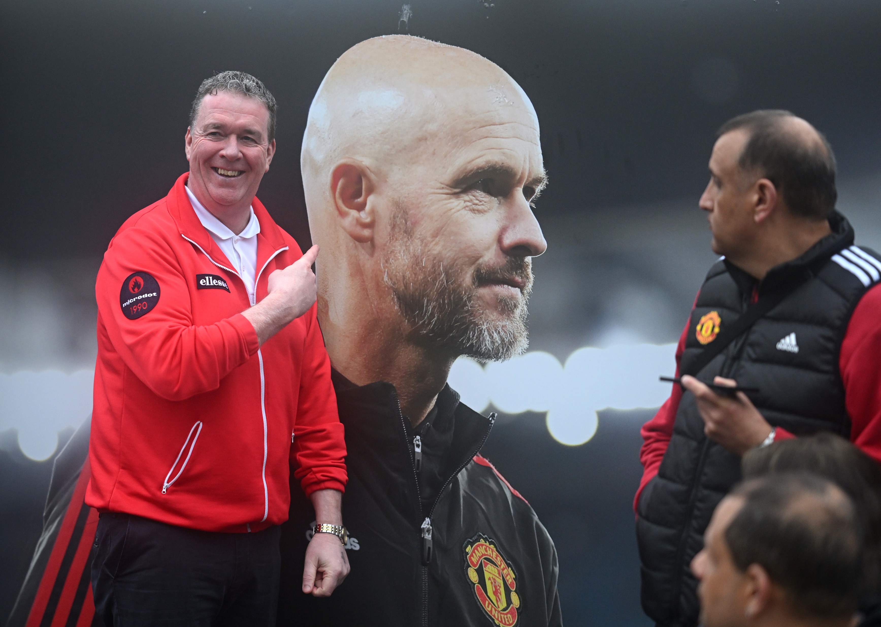 Manchester United fan laughs and points at photo of Erik ten Hag.
