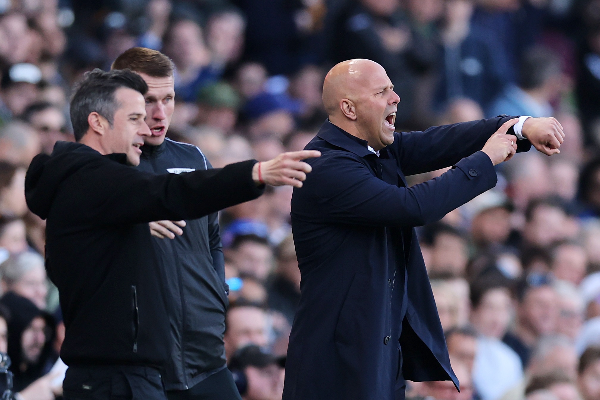 Arne Slot shouts at Liverpool players while pointing at his wrist.