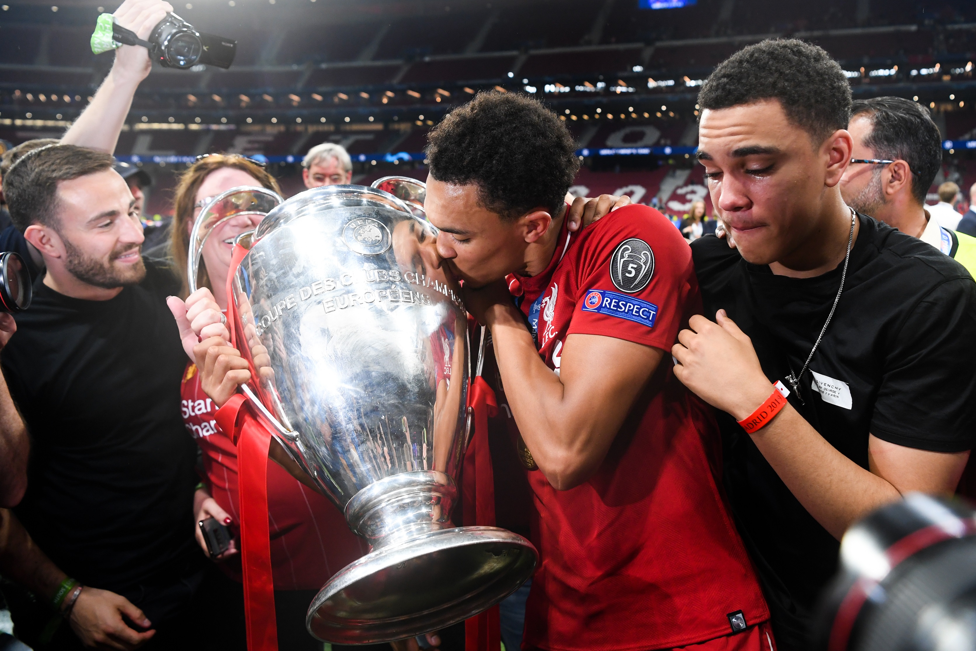 Trent Alexander-Arnold kisses the Champions League trophy next to brother Marcell.