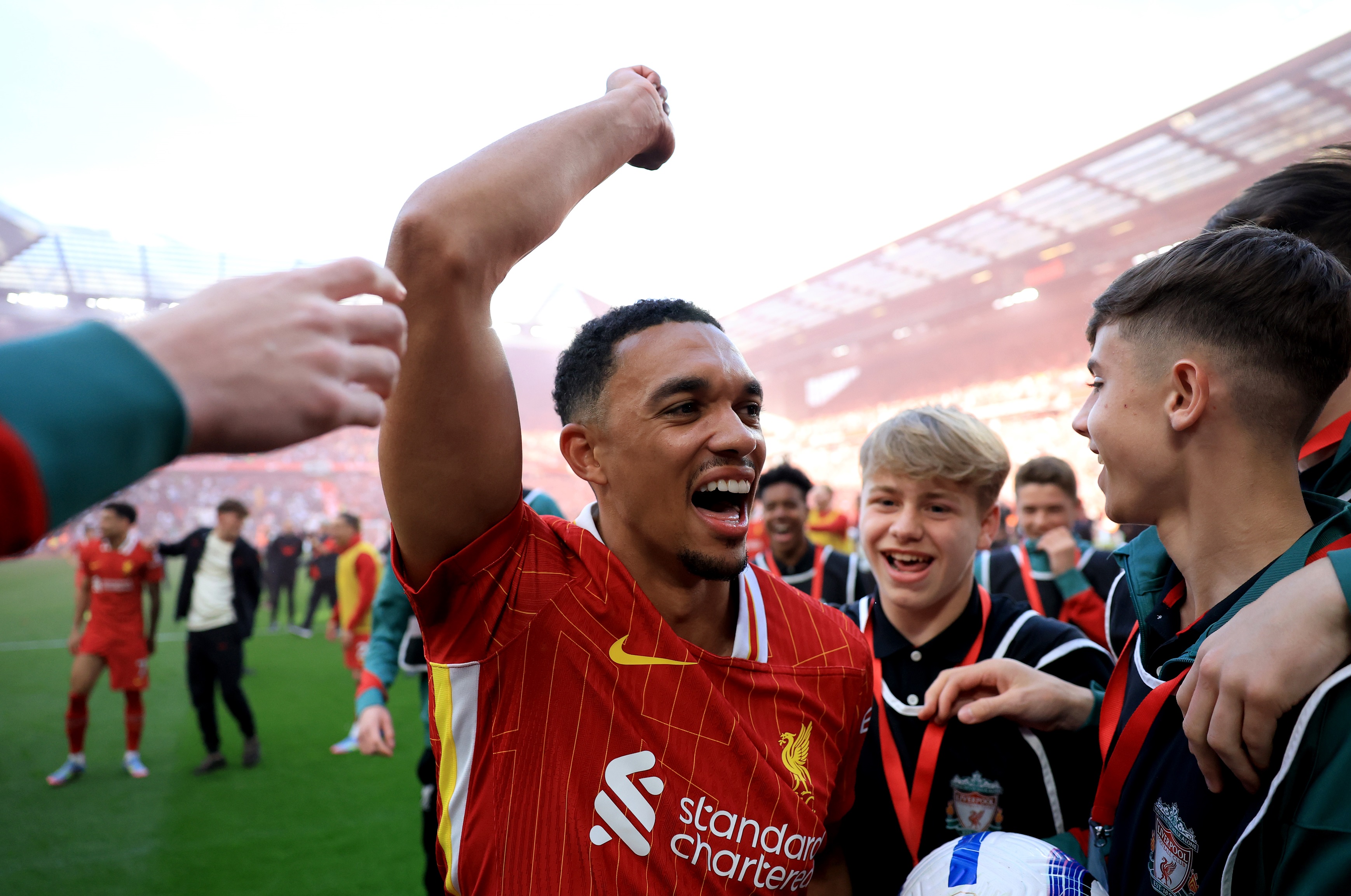 Trent Alexander-Arnold celebrates at Anfield with his arms in the air.