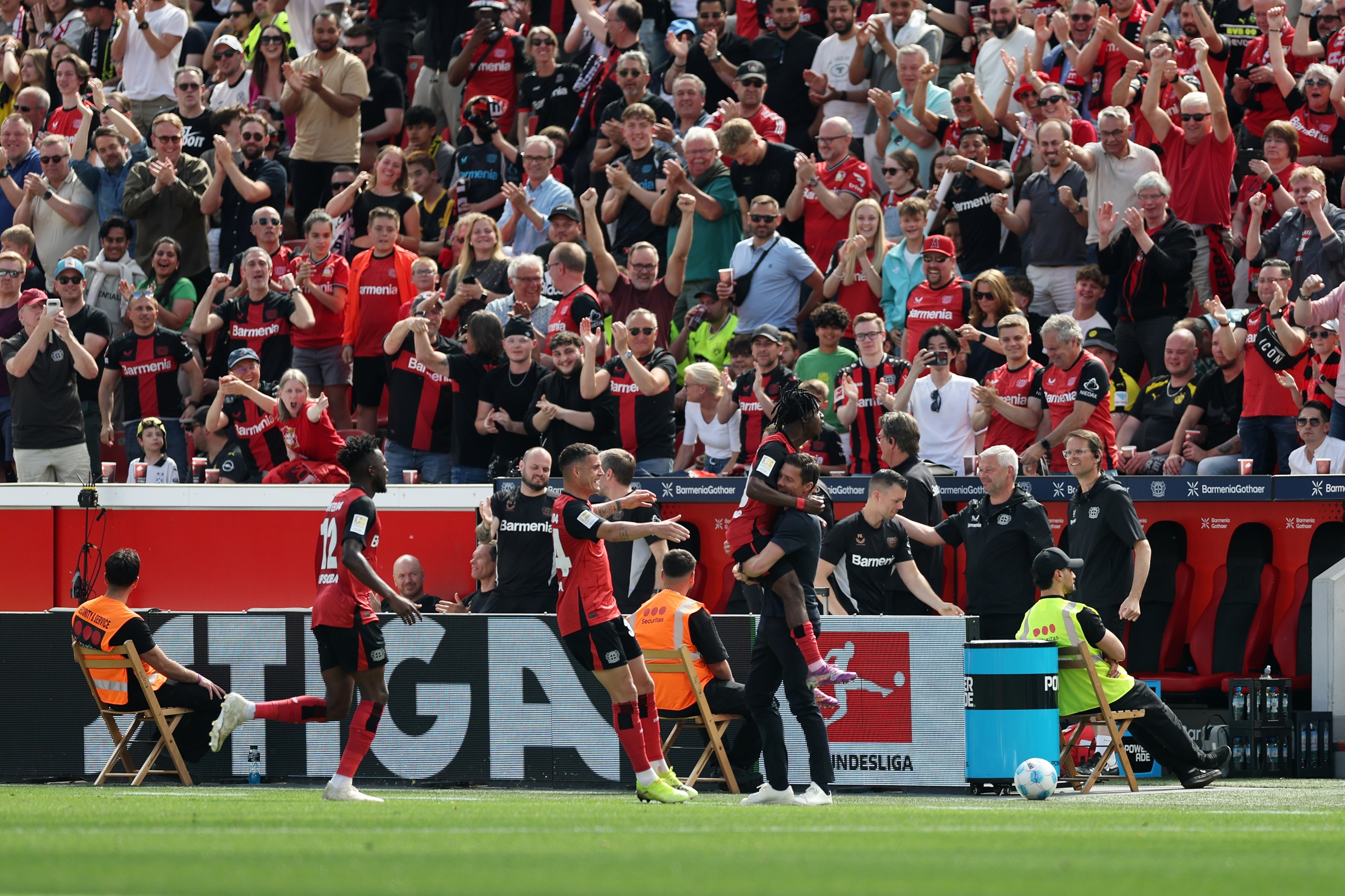 Jeremie Frimpong jumps into Xabi Alonso's arms on the touchline.