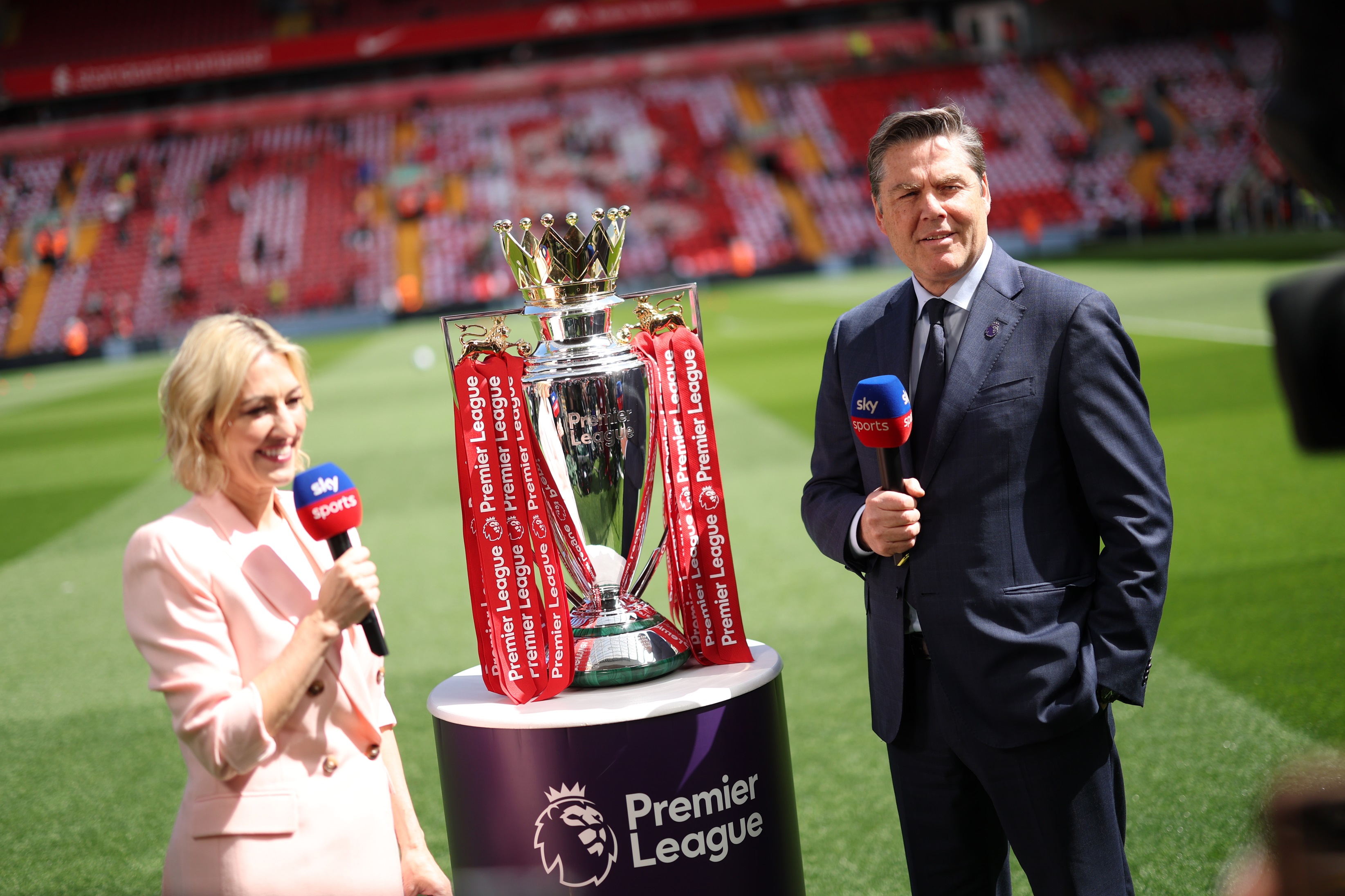 Kelly Cates and Richard Masters stand next to the Premier League trophy.