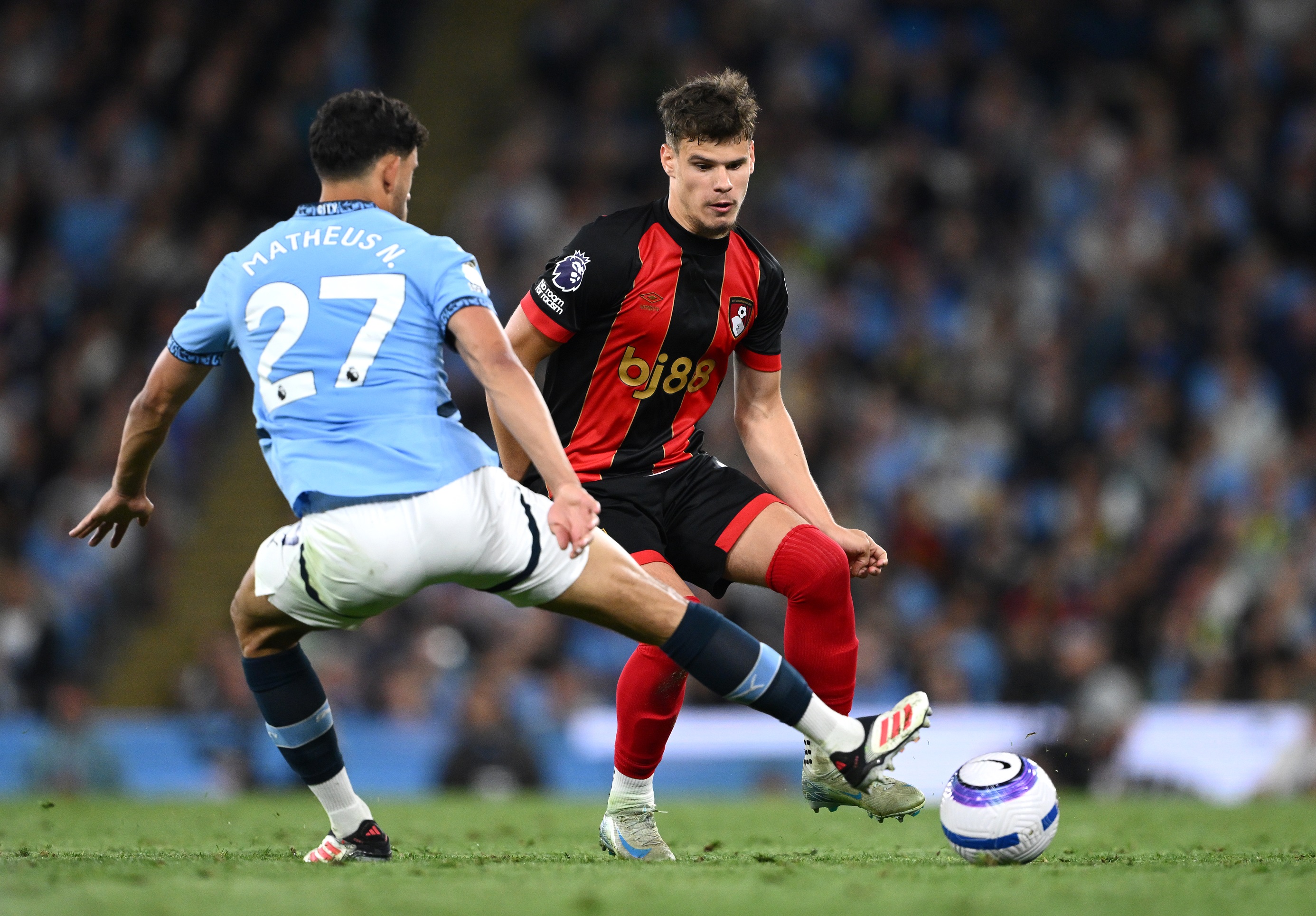 Milos Kerkez passes the ball whilst under pressure from Matheus Nunes.