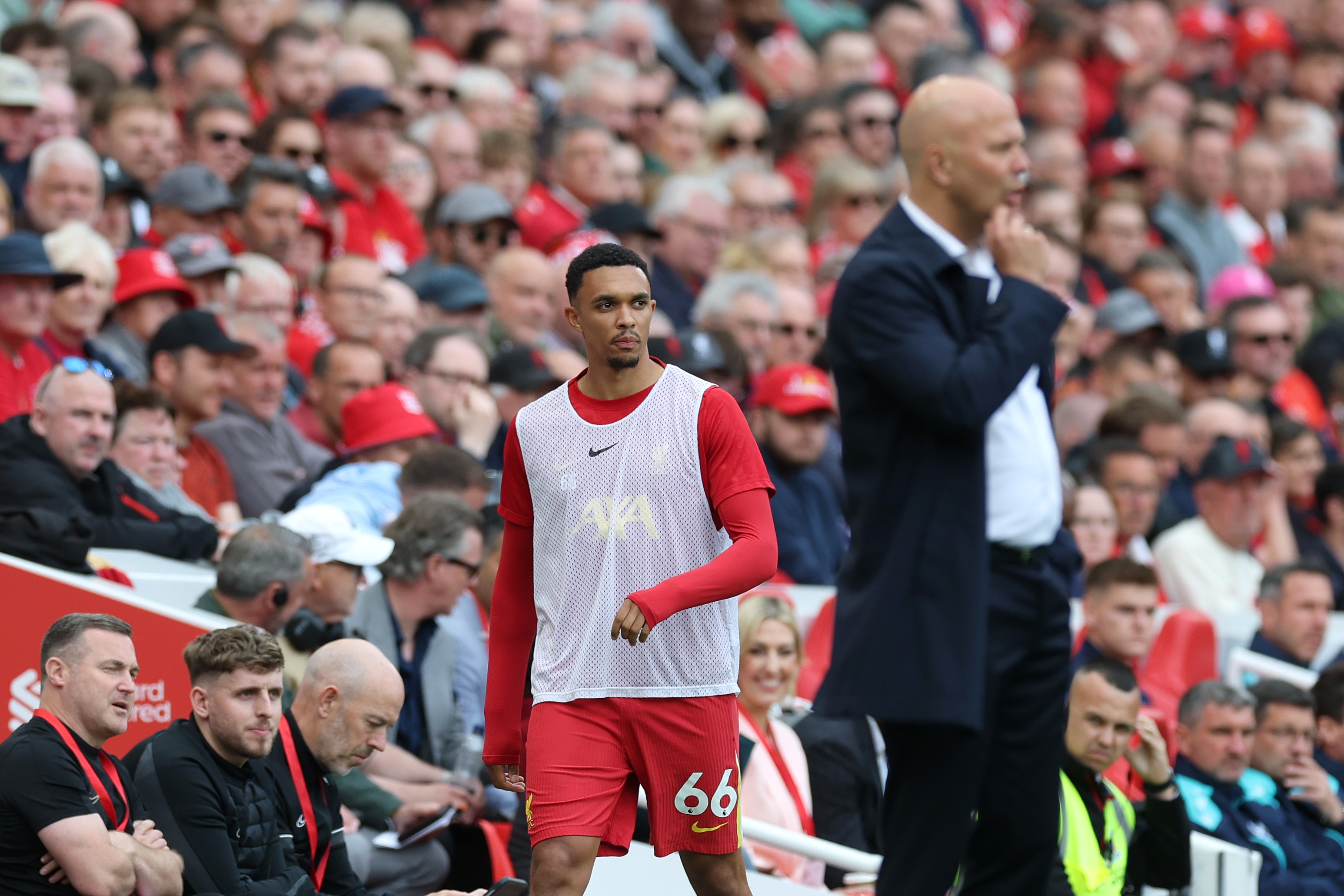 Trent Alexander-Arnold walks on the touchline behind head coach Arne Slot.