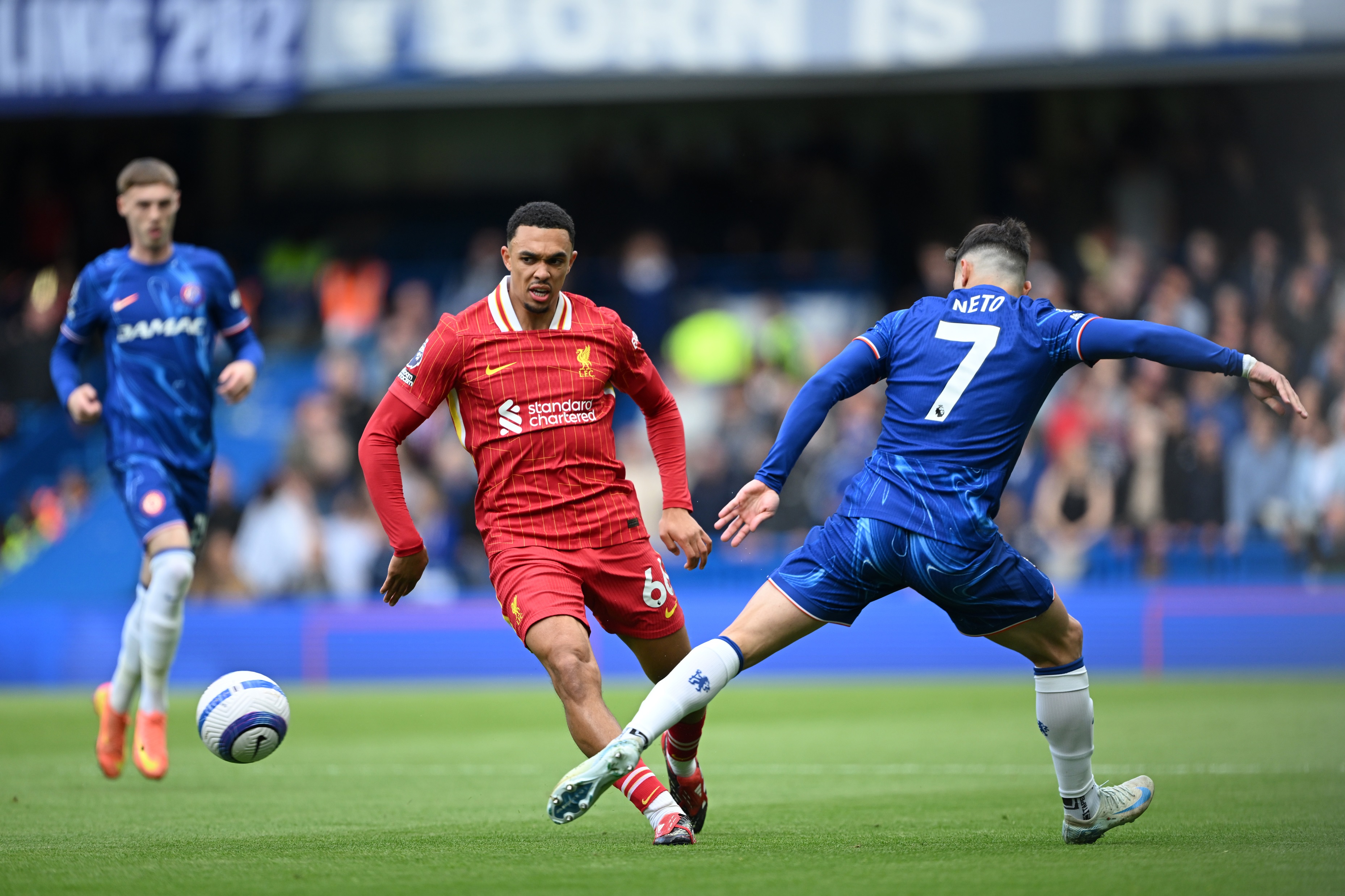 Trent Alexander-Arnold passes the ball away from the trailing leg of Pedro Neto.