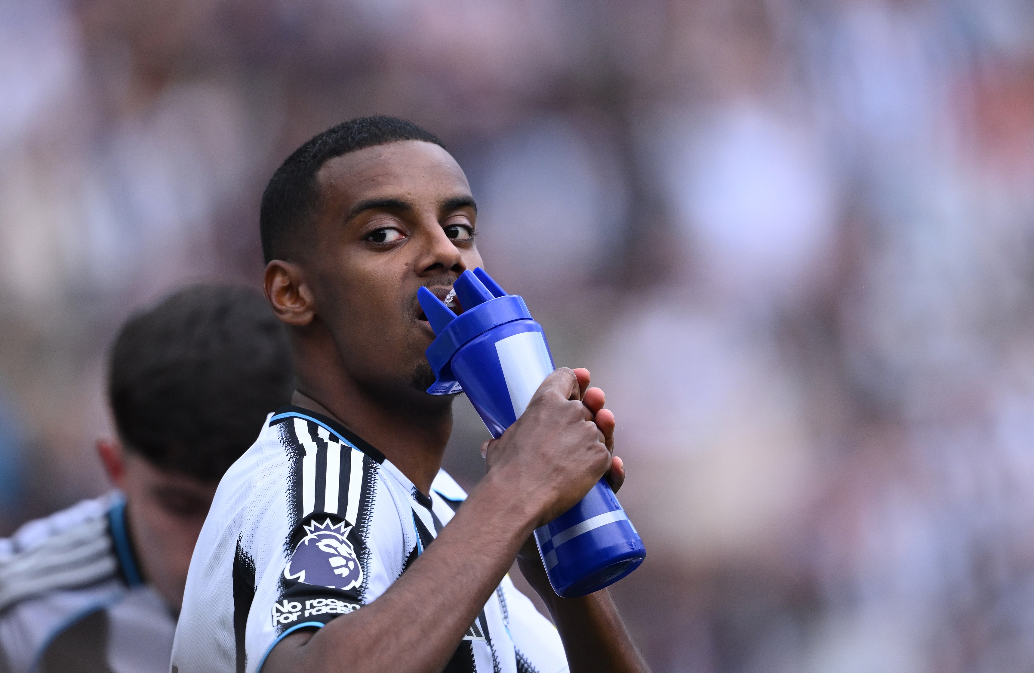 Alexander Isak drinks from a water bottle on the pitch.
