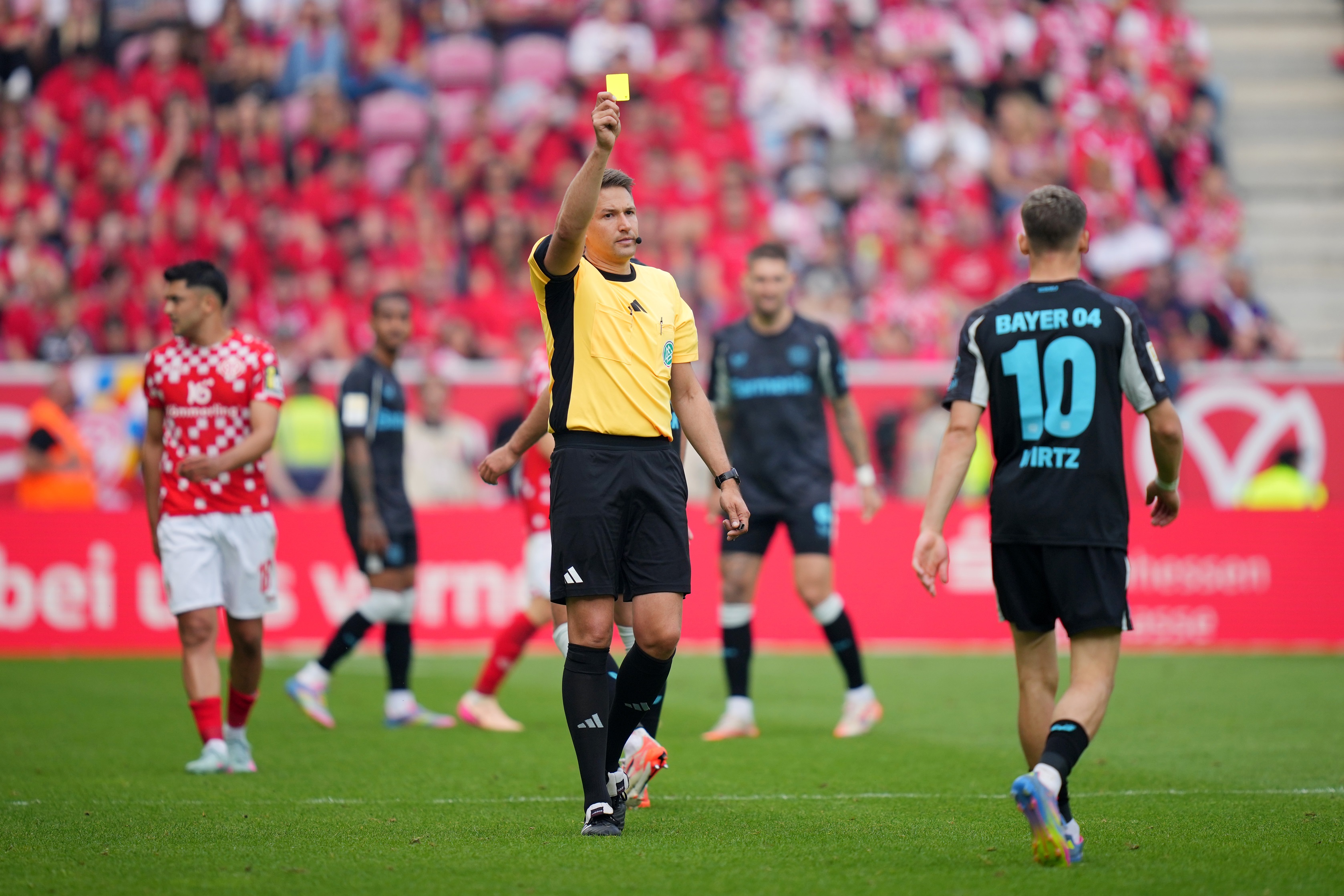 Florian Wirtz is shown a yellow card by the referee.