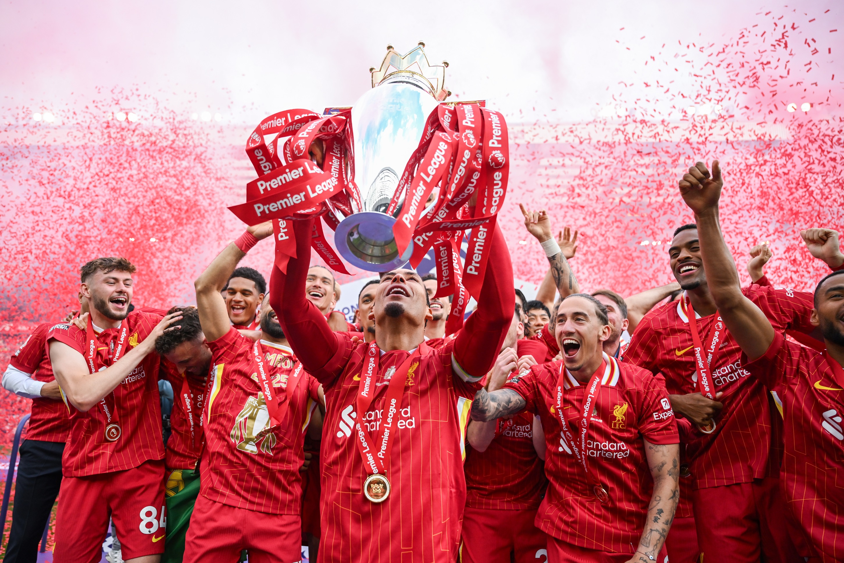 Virgil van Dijk lifts the Premier League trophy amid a sea of red confetti.