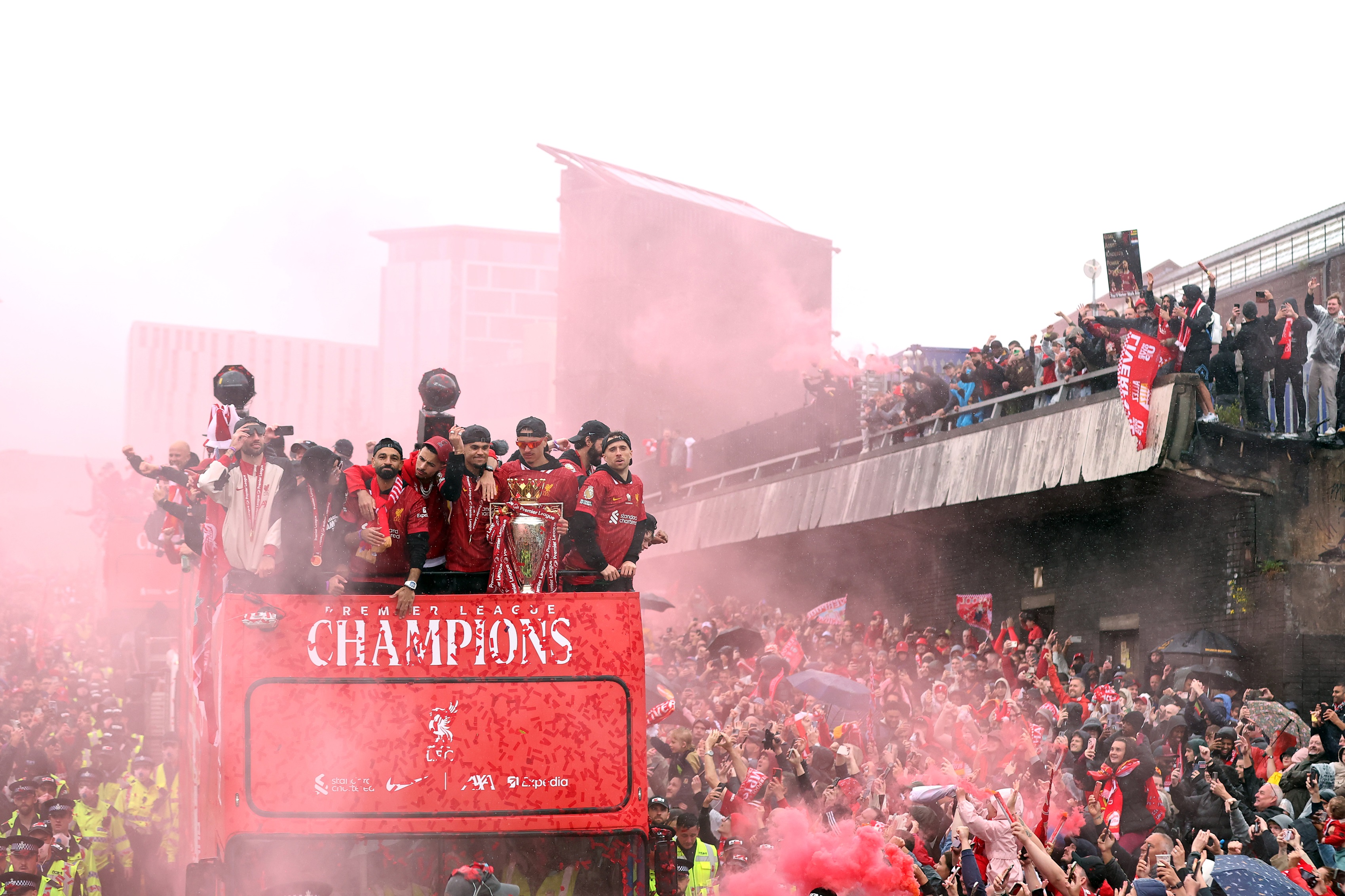 Liverpool players celebrate Premier League trophy win on open-top bus.