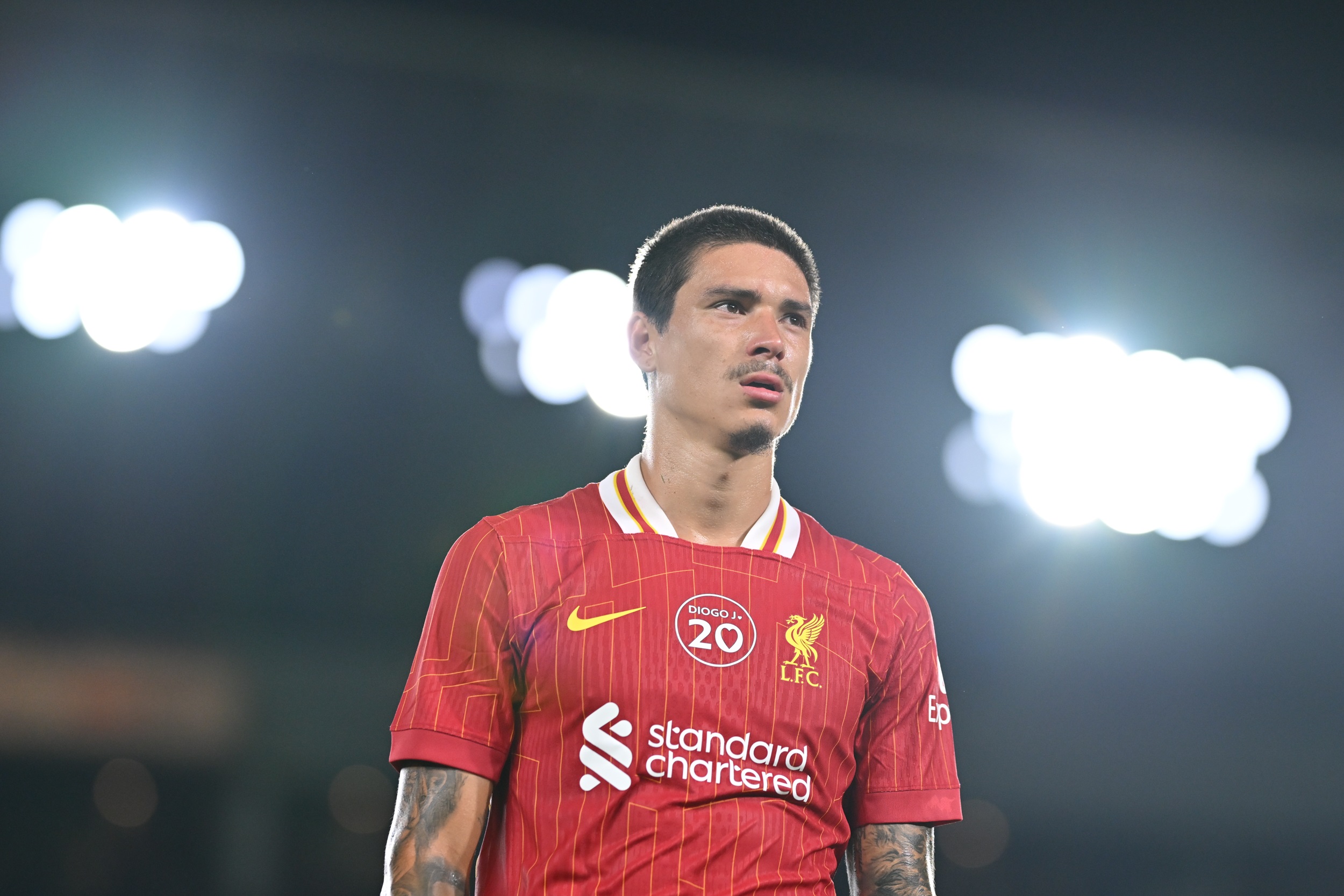 Darwin Nunez looks on in front of a background of floodlights.