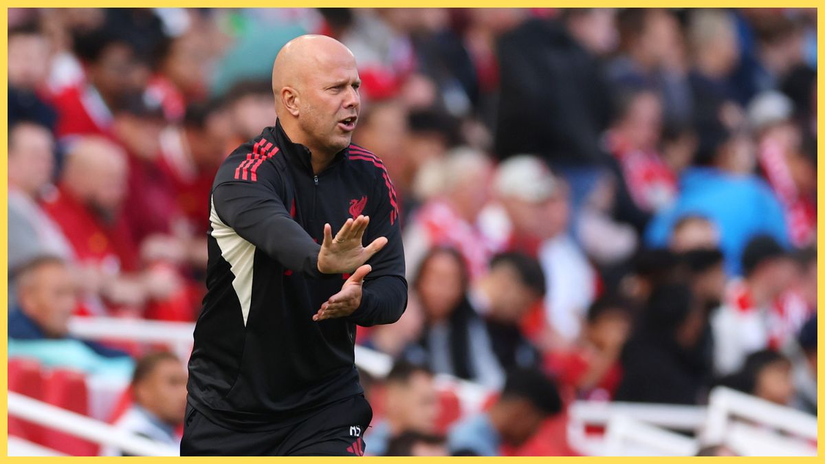 Arne Slot pushes out his hand whilst looking at the pitch.