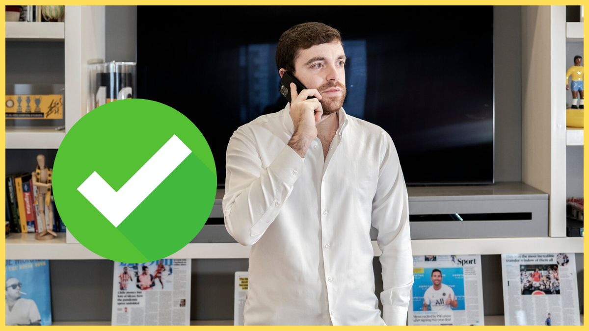 Fabrizio Romano holds his phone to his ear in front of a bookcase.