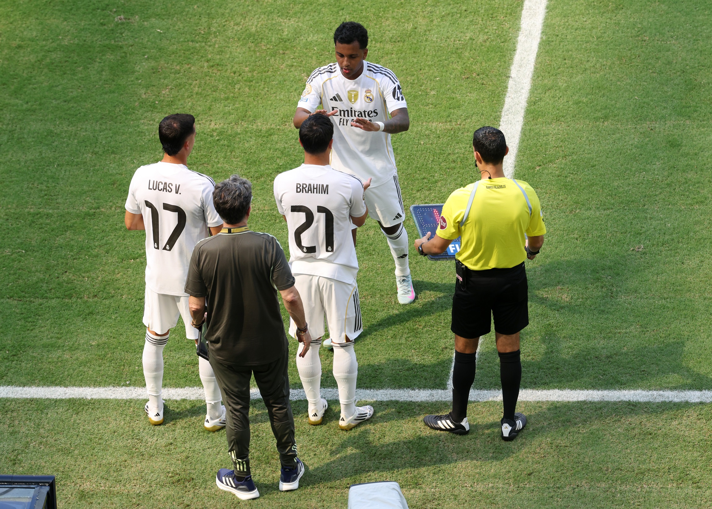 Rodrygo high fives a Real Madrid teammate on the touchline.