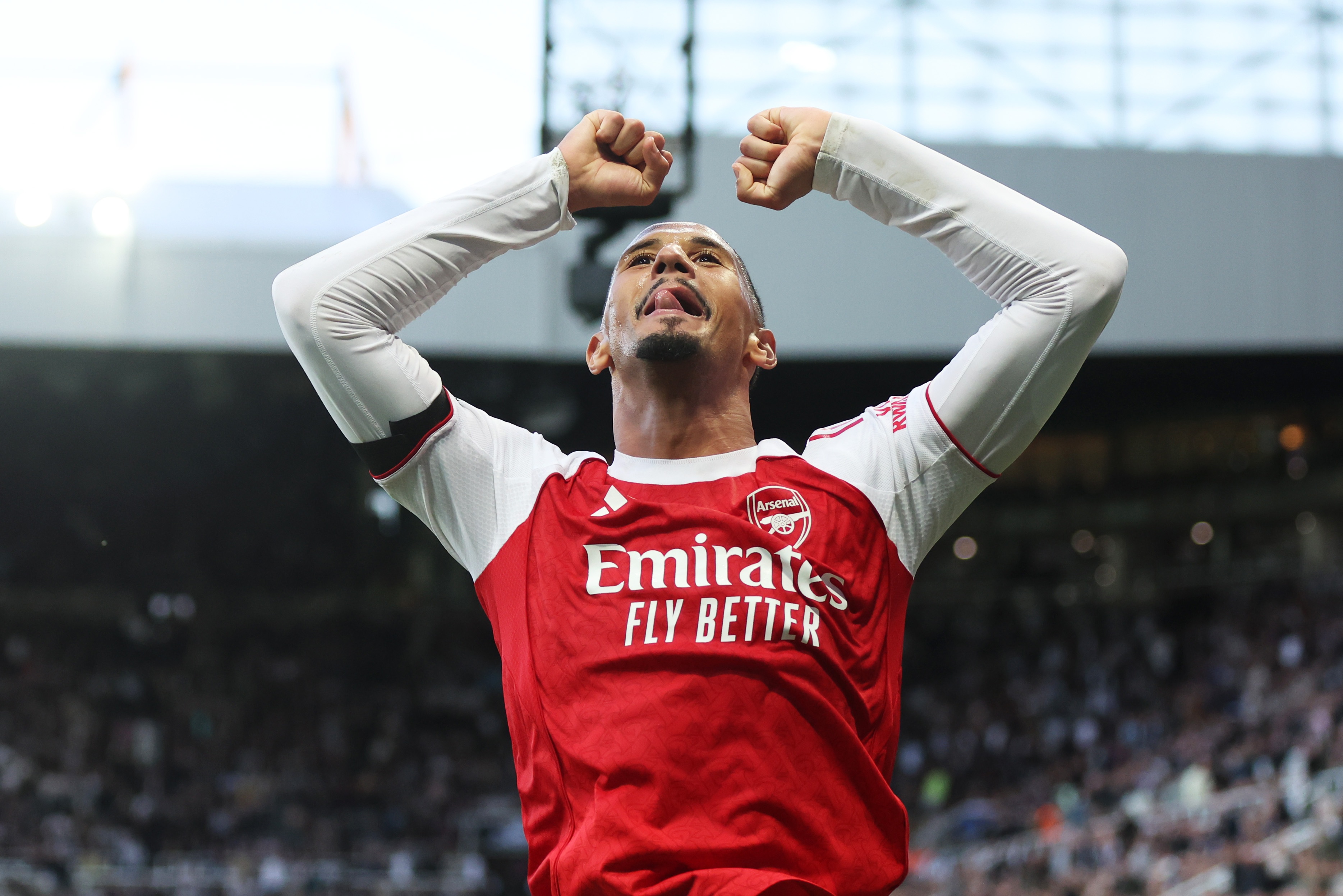 William Saliba celebrates with his arms bent up in the air at St James Park.