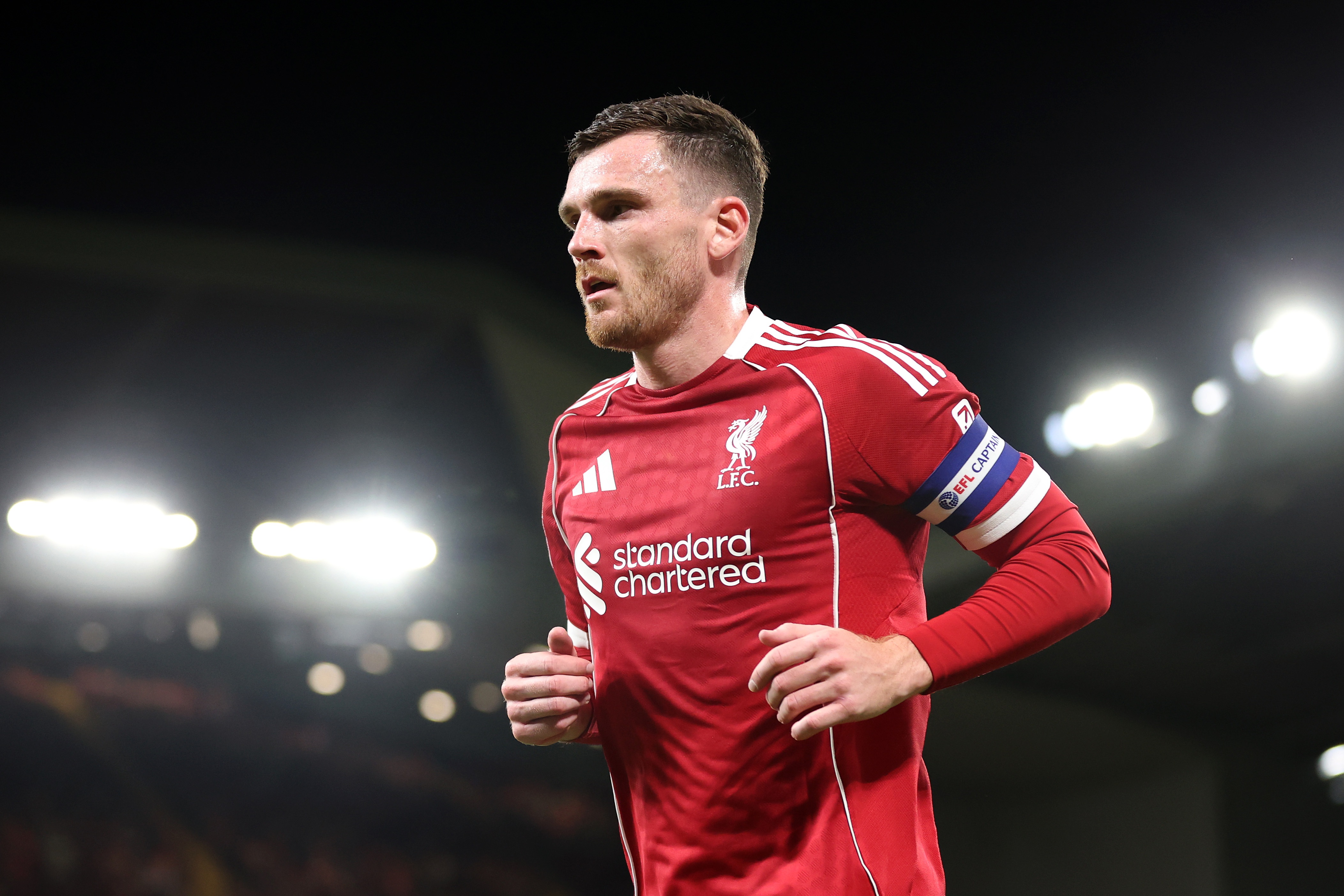 Andy Robertson runs on the pitch under the floodlights.
