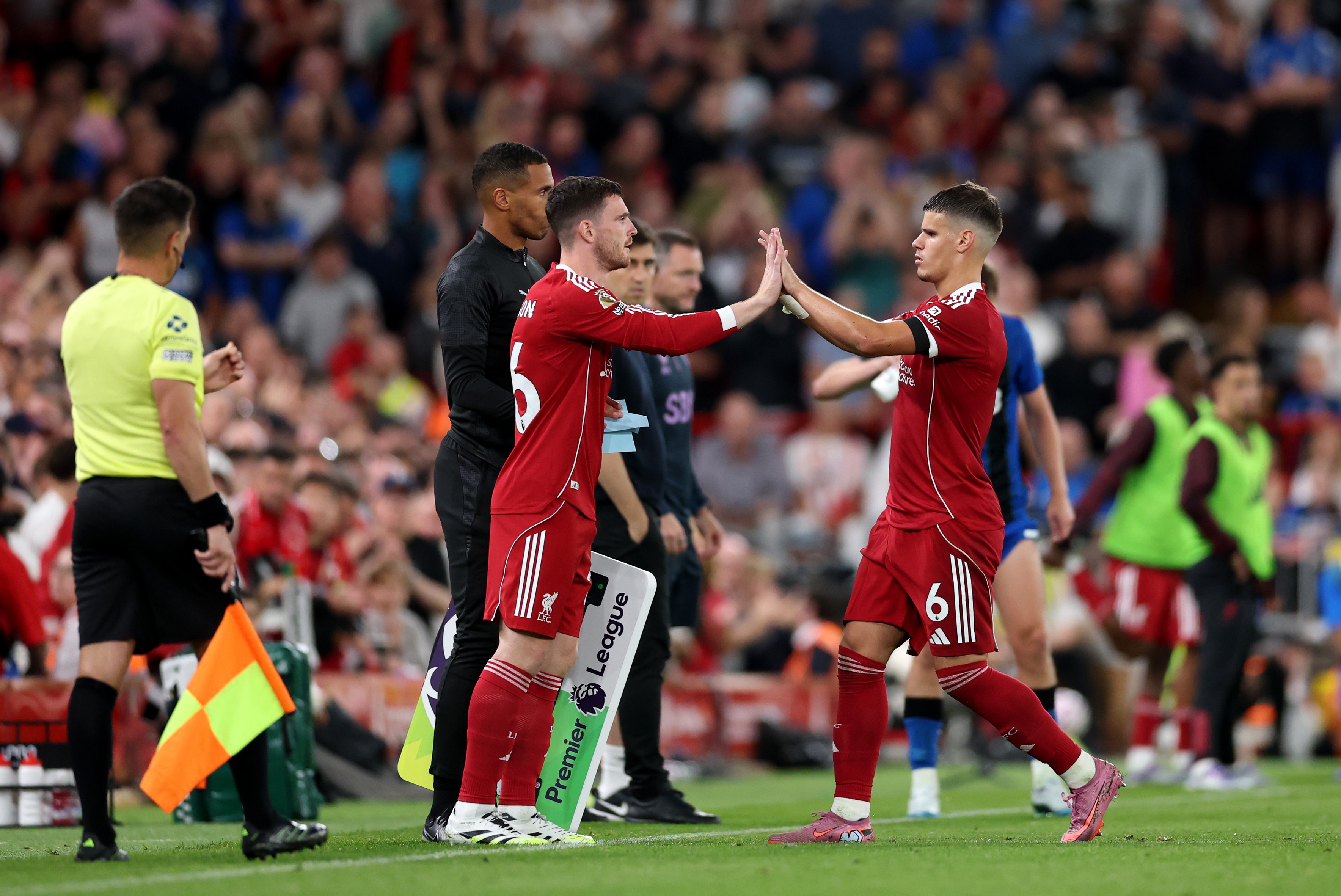 Andy Robertson high fives Liverpool F.C. teammate Milos Kerkez on the touchline.