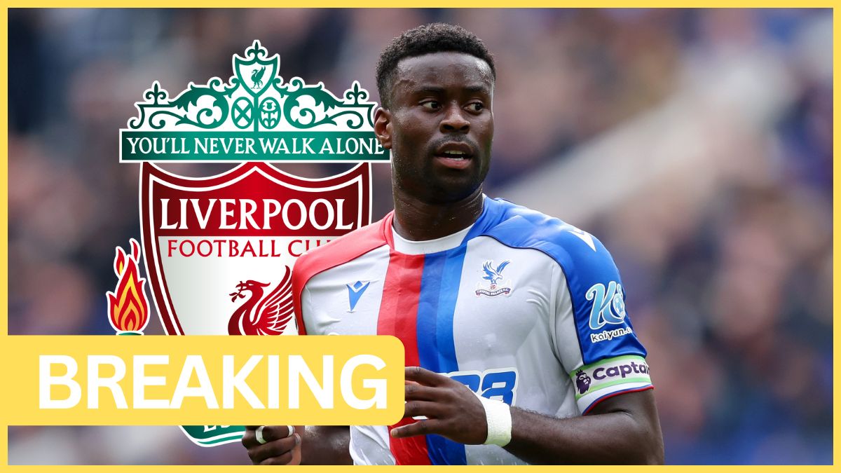 Marc Guehi looks over his left shoulder with Liverpool club crest in the background.