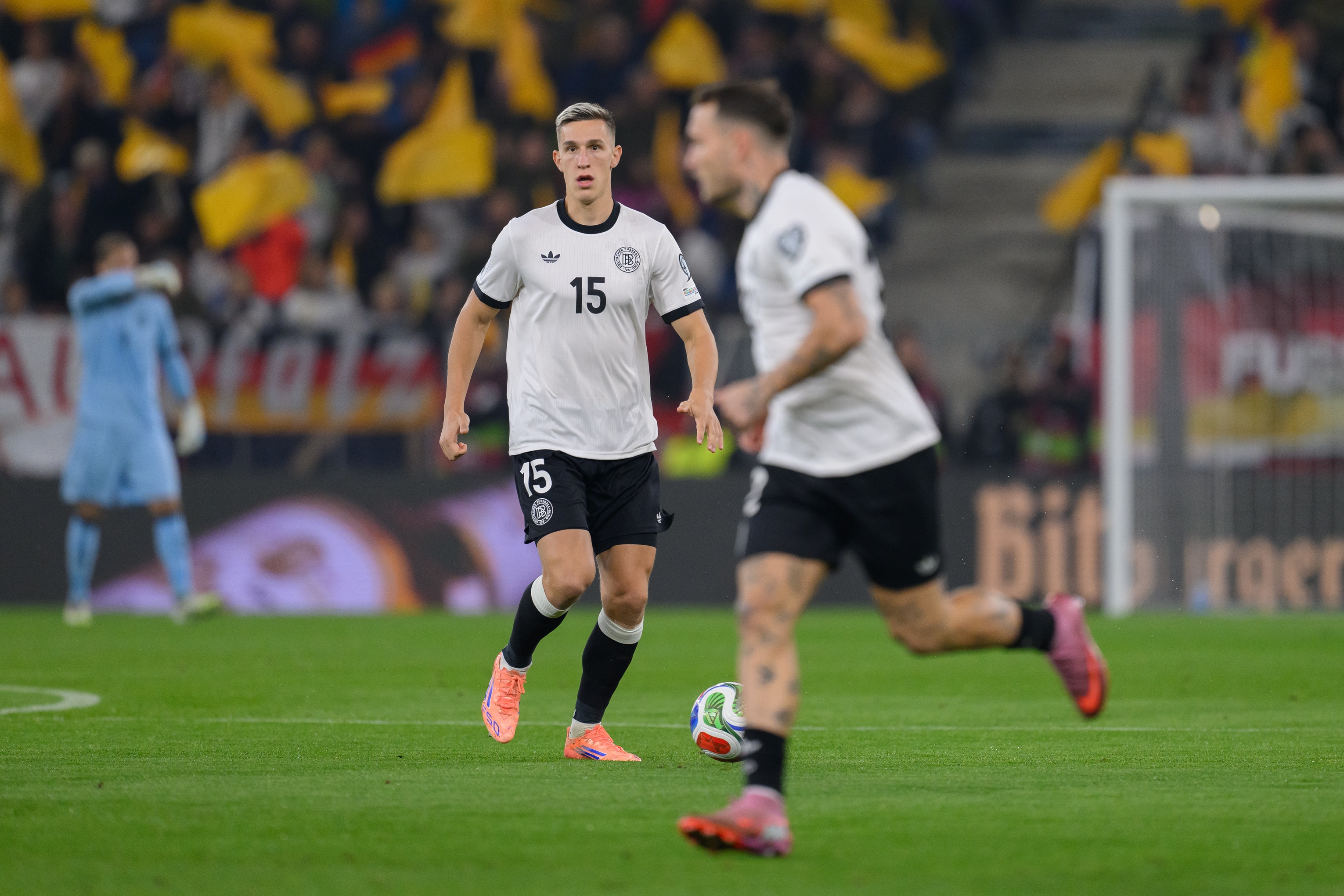 Nico Schlotterbeck dribbles with the ball while Germany player runs in front of him.