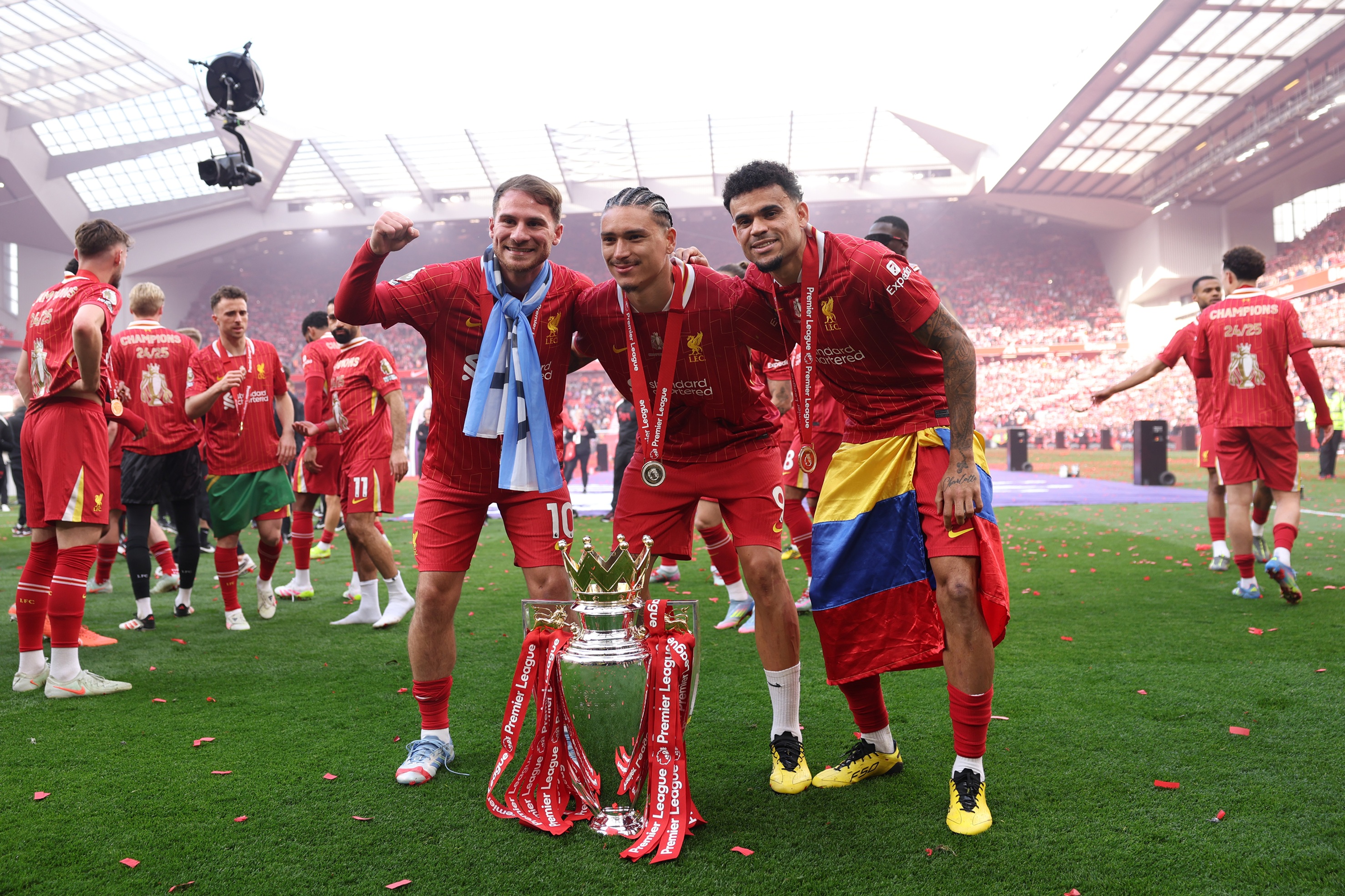 Luis Diaz, Darwin Nunez and Alexis Mac Allister celebrate in front of Premier League trophy.