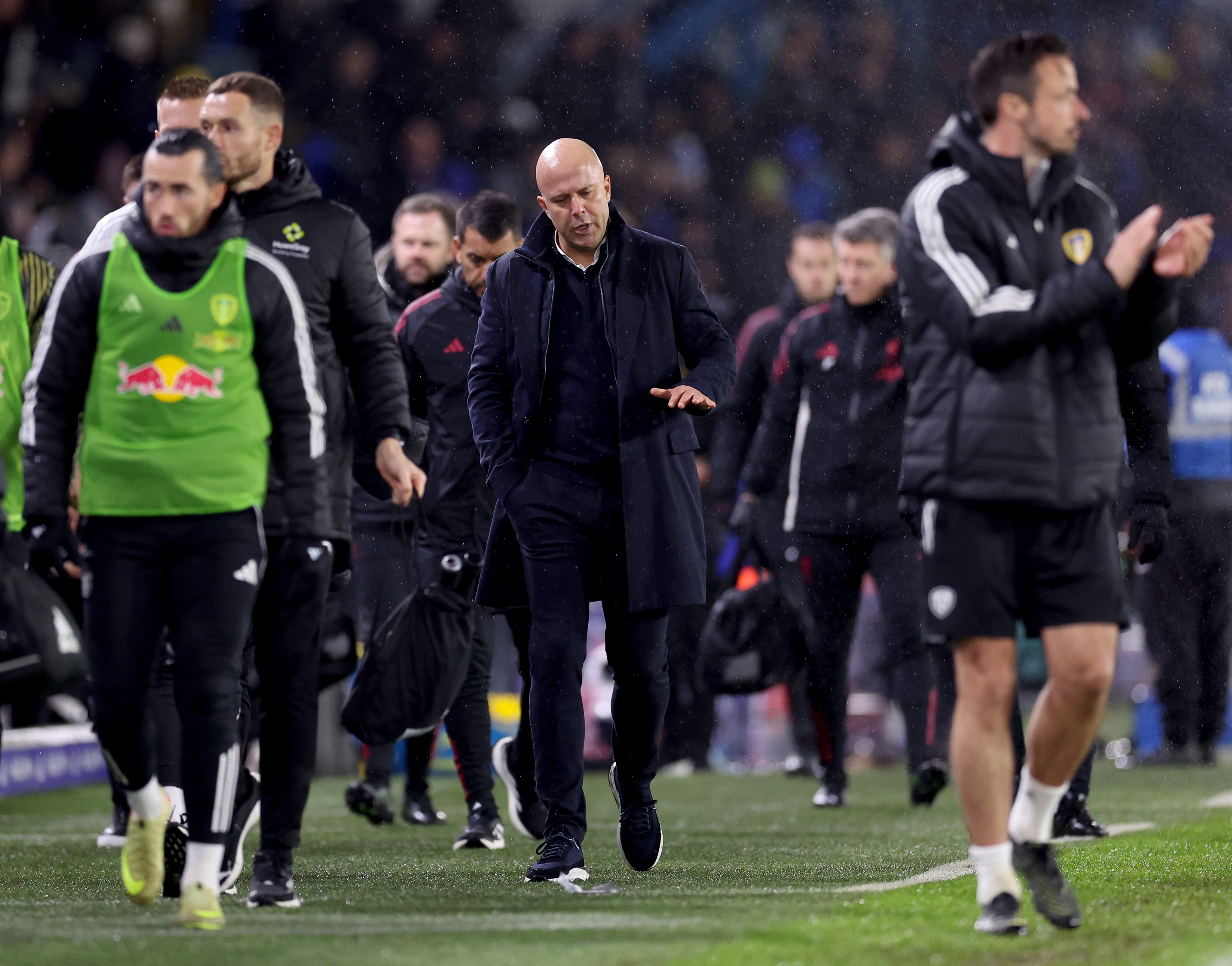 Arne Slot gestures while walking on the pitch at Elland Road.