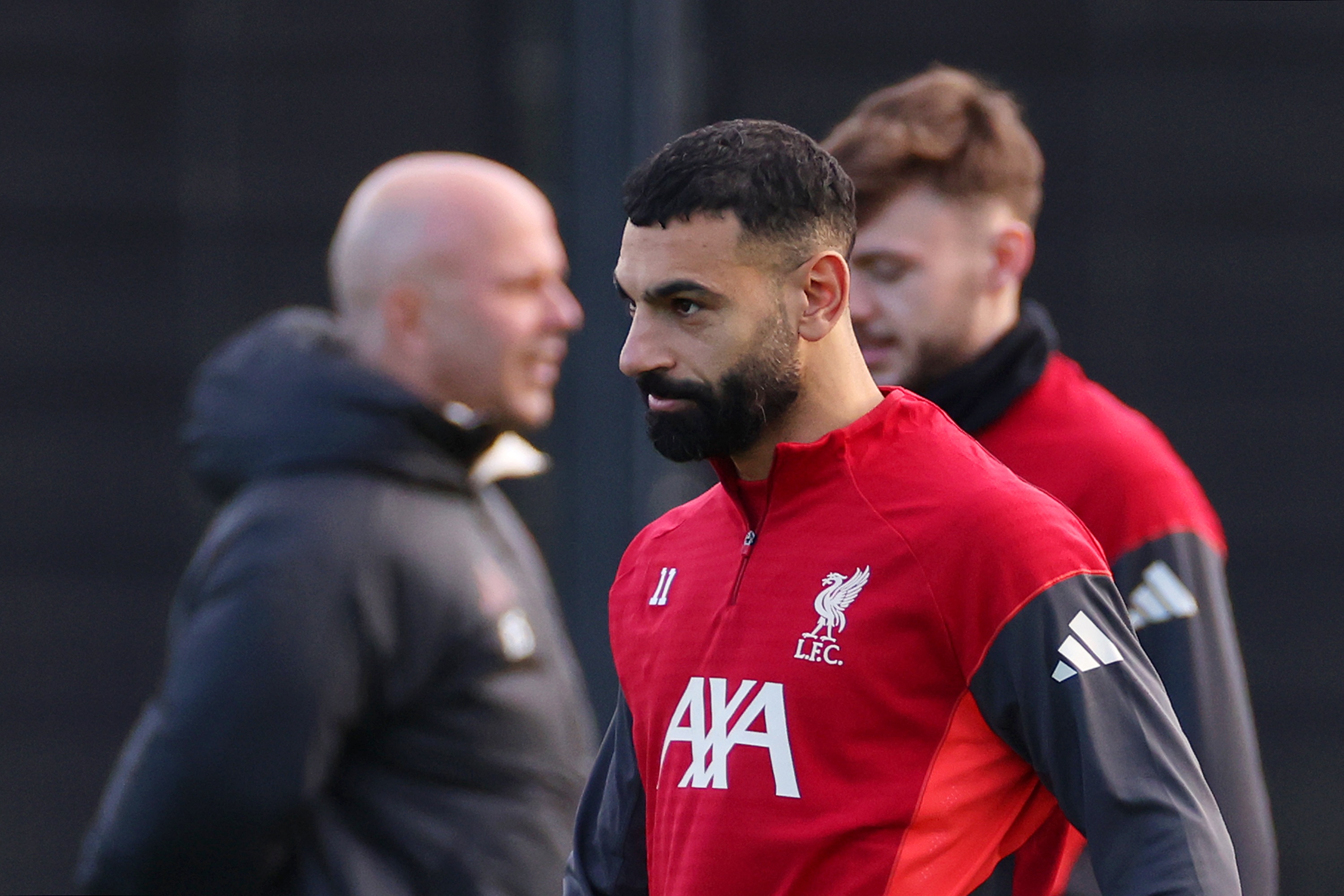 Arne Slot blurry in the background behind Mo Salah in the foreground.