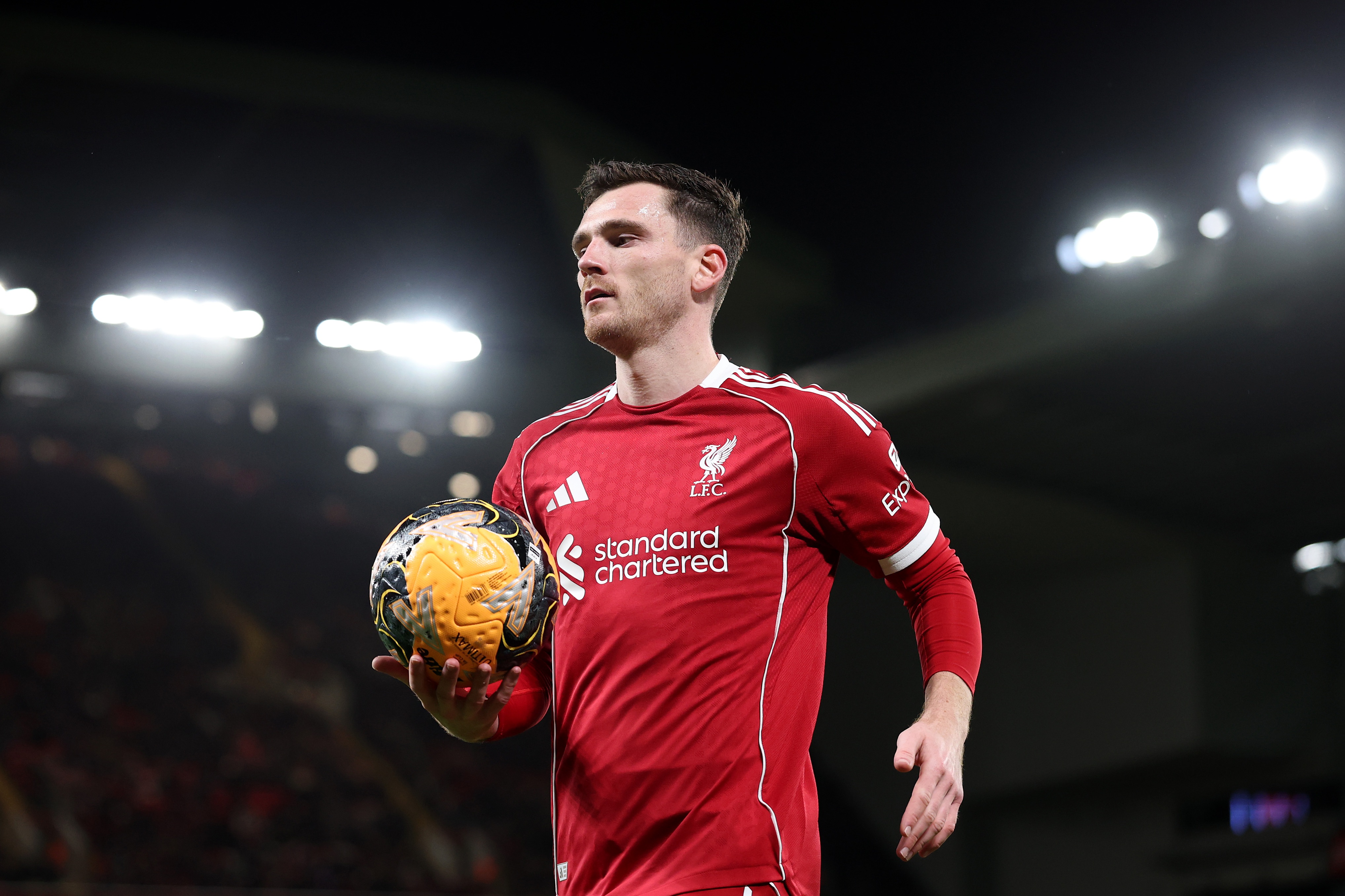 Andy Robertson carries the ball in his right hand.