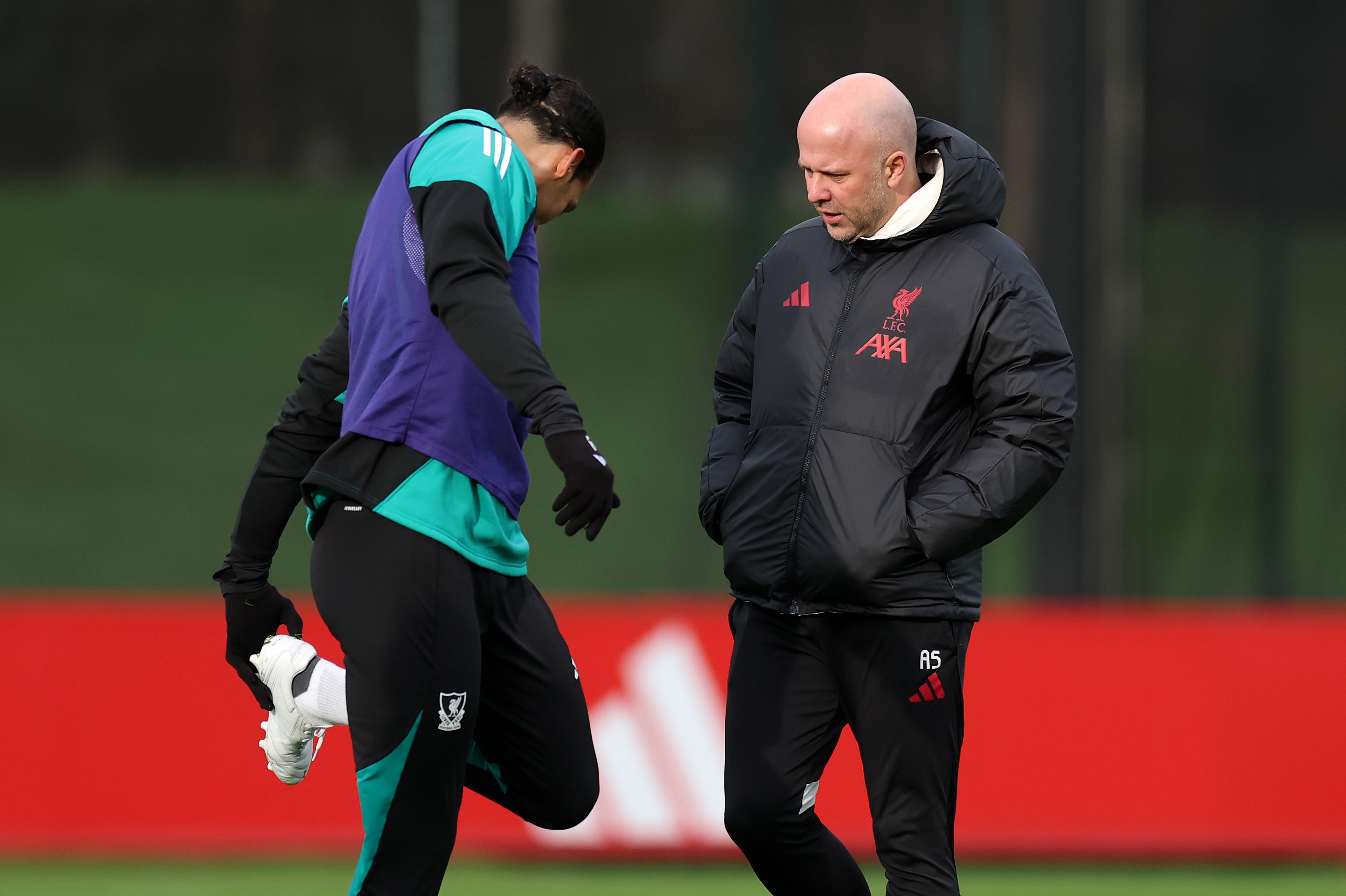 Virgil van Dijk touches his left boot while speaking to Arne Slot.