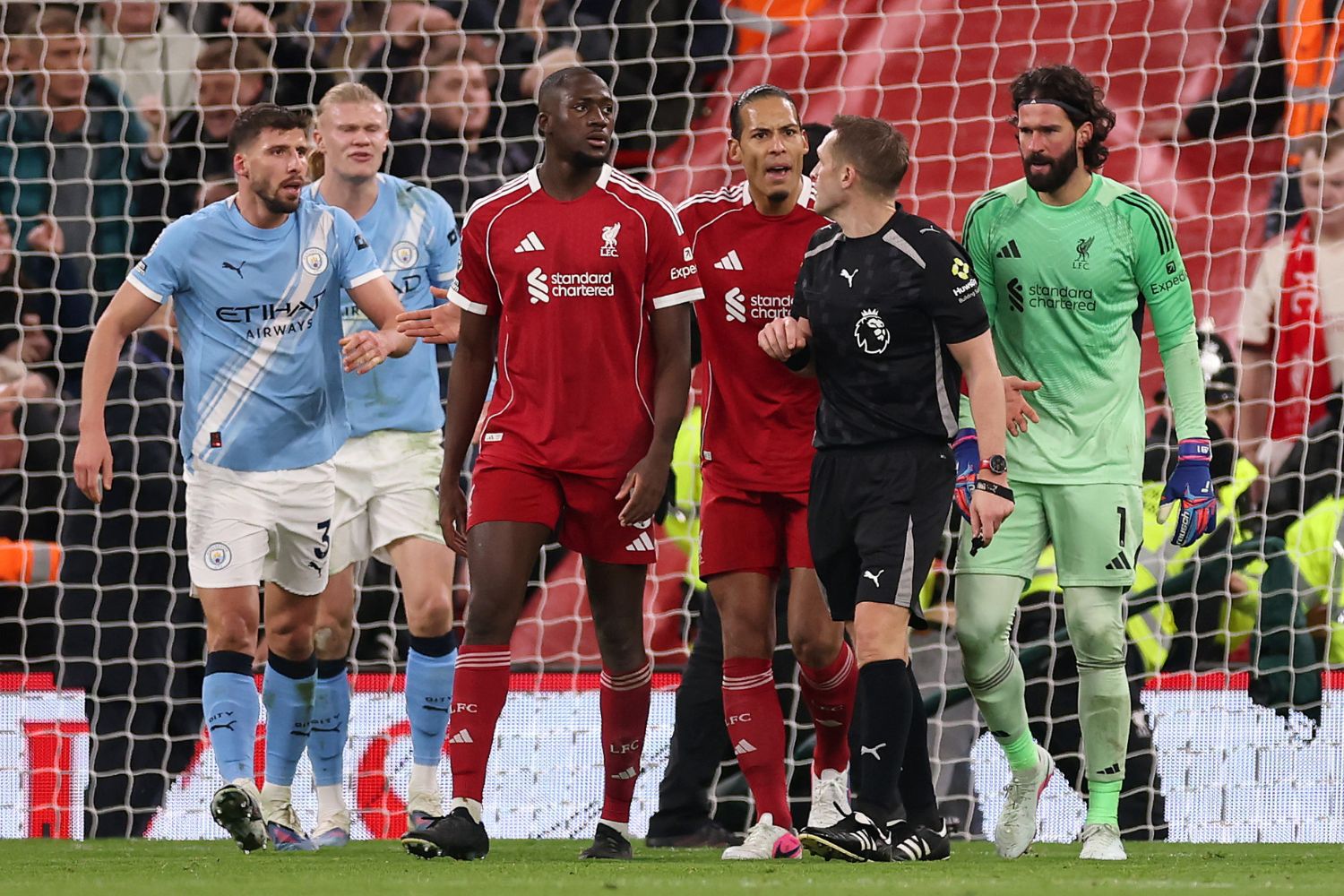 Craig Pawson speaks with players as Ruben Dias of Manchester City reacts with Ibrahima Konate and Virgil van Dijk of Liverpool during the Premier League match between Liverpool and Manchester City