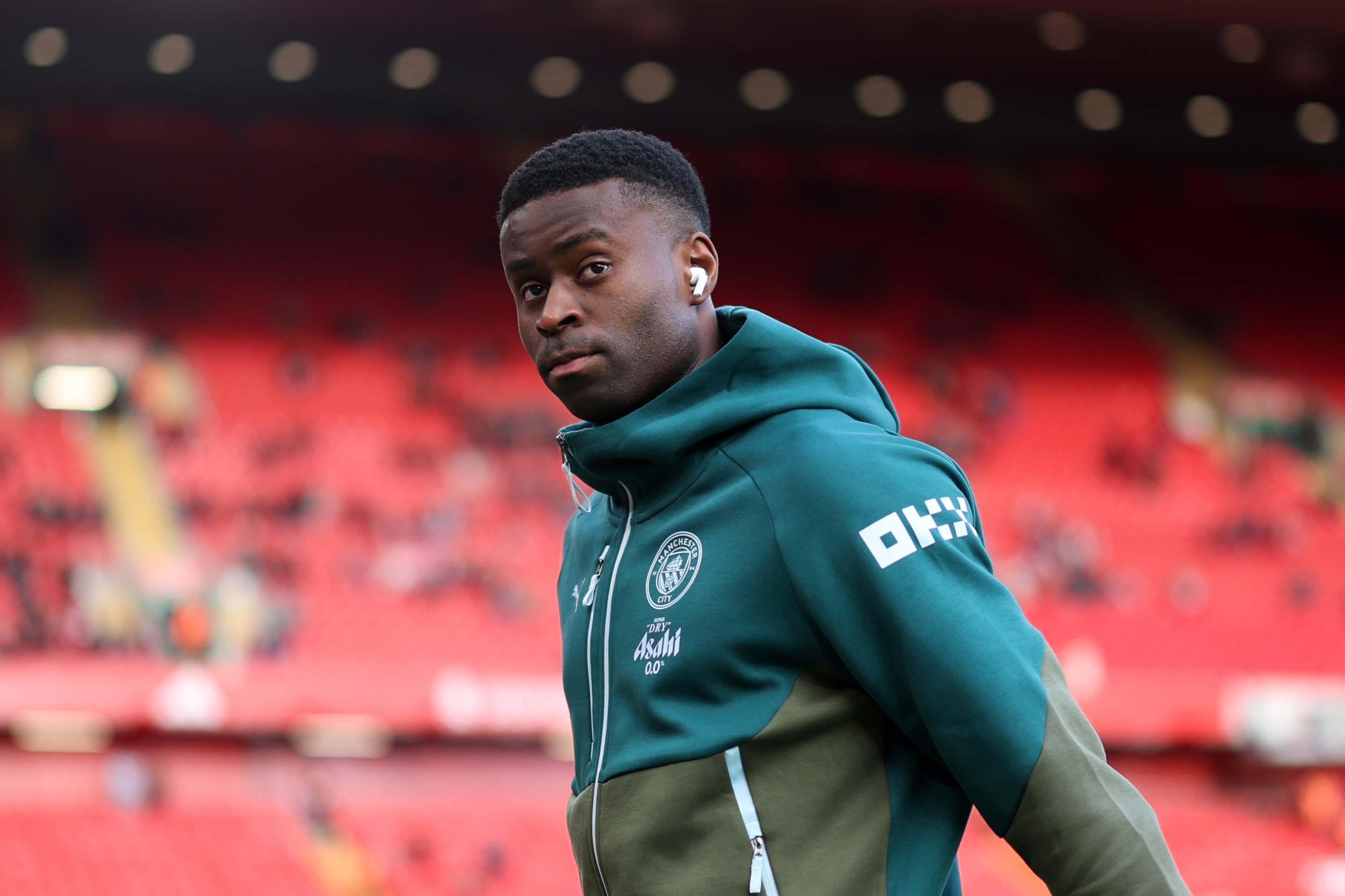 Marc Guehi walks on the pitch at Anfield in a Man City tracksuit.