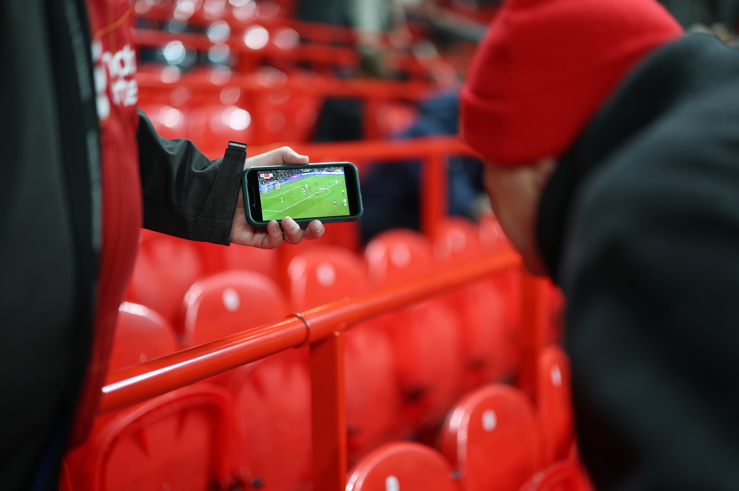 Liverpool fans watch a game on a smartphone prior to a match at Anfield
