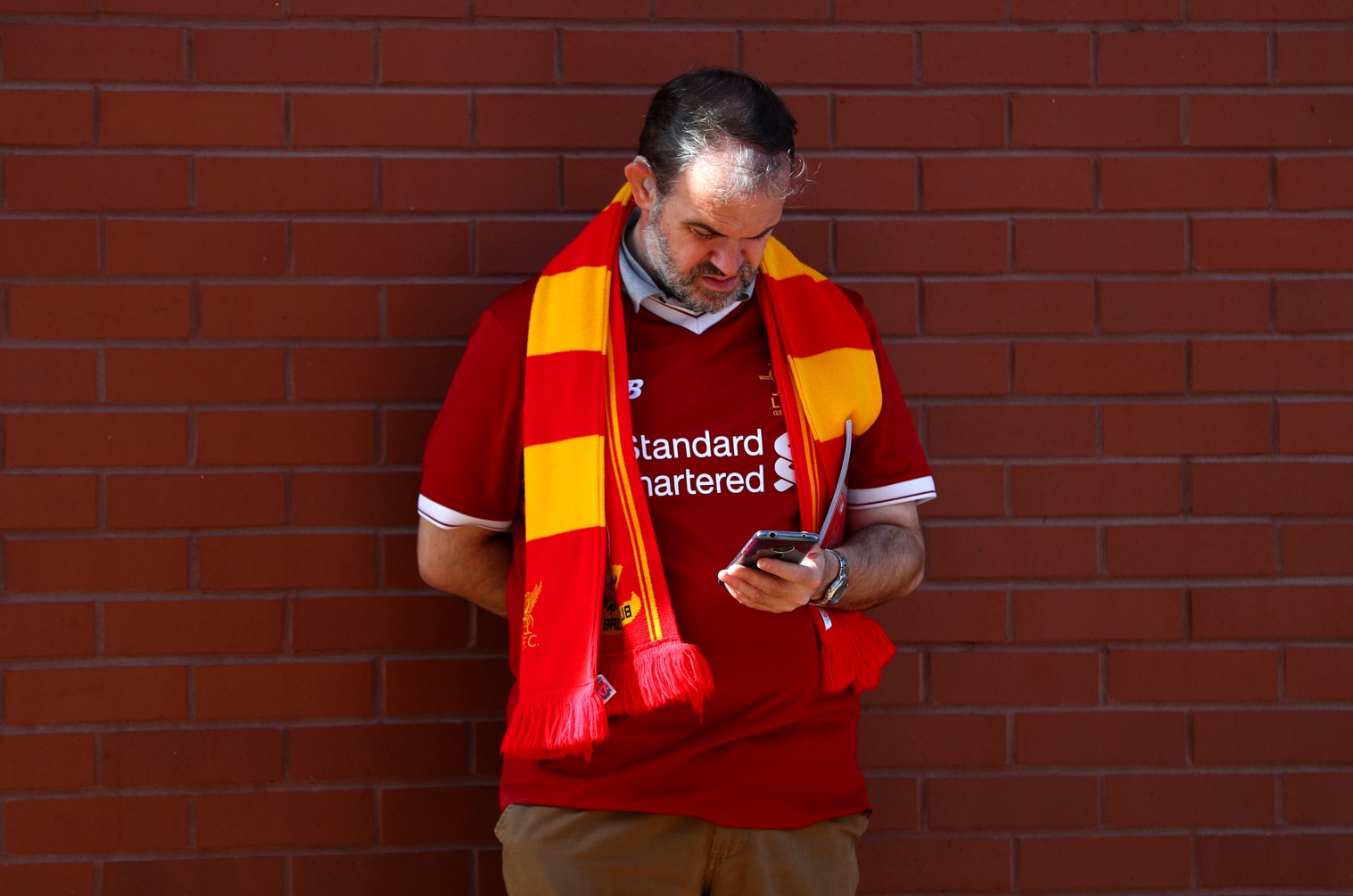 A Liverpool fan browsing on his smartphone before a match at Anfield