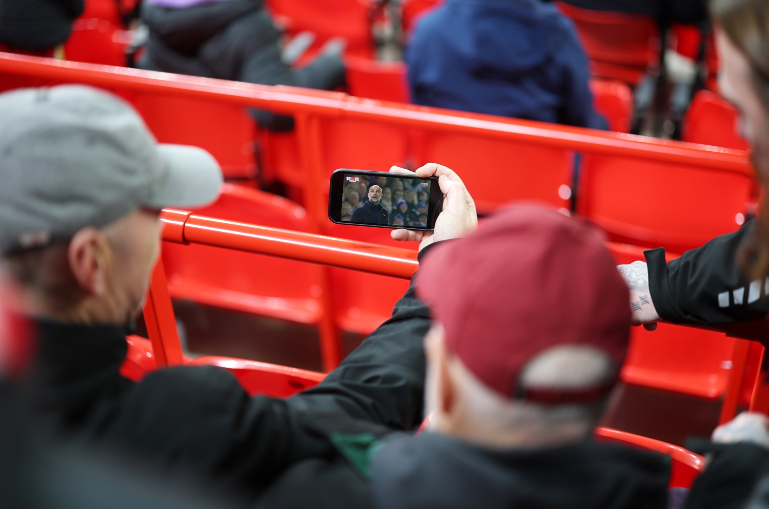 A Liverpool fan watching football on his phone prior to a match at Anfield