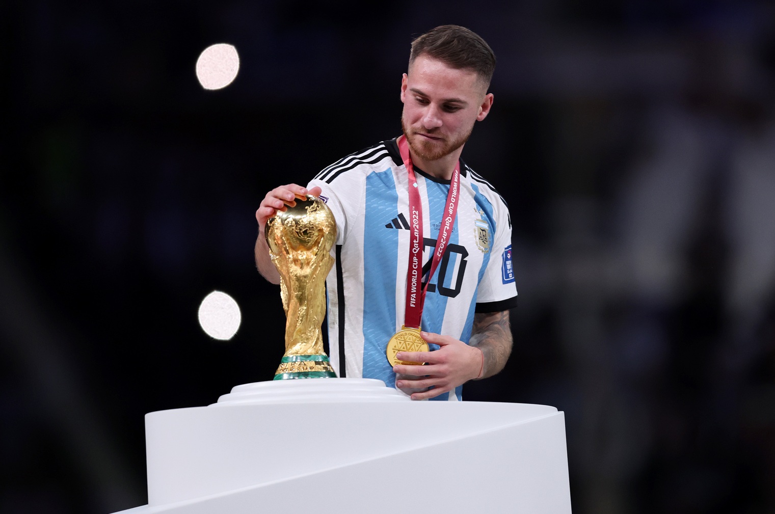 Alexis Mac Allister pets the World Cup trophy after Argentina's triumph in 2022
