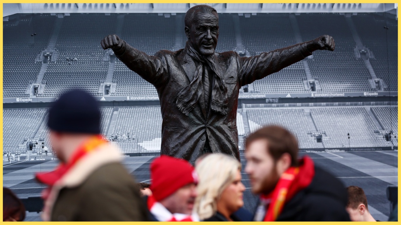 Liverpool fans walk past the statue of Bill Shankly outside Anfield