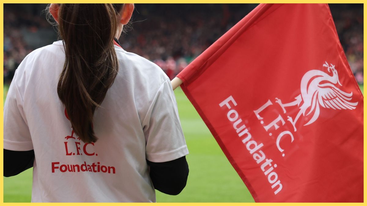 Young girl wearing an LFC Foundation shirt and waving an LFC Foundation flag